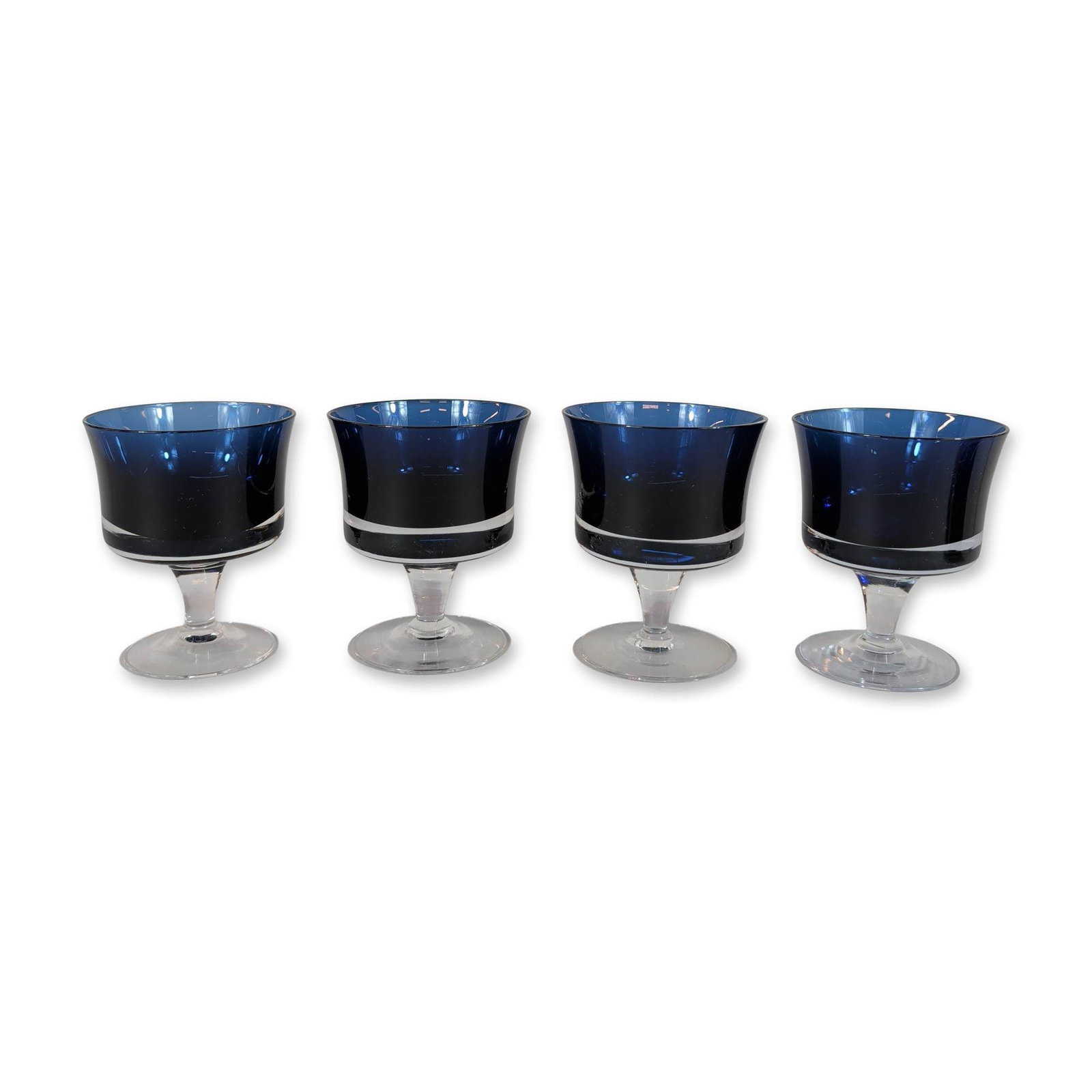 Set of Four Denby Style Mirage Blue Stemmed Glasses: Denby stemmed glasses in the Mirage Blue pattern, constructed of cobalt blue and clear glass. Each vessel features a flared bowl in deep cobalt blue with a decorative clear horizontal band near the