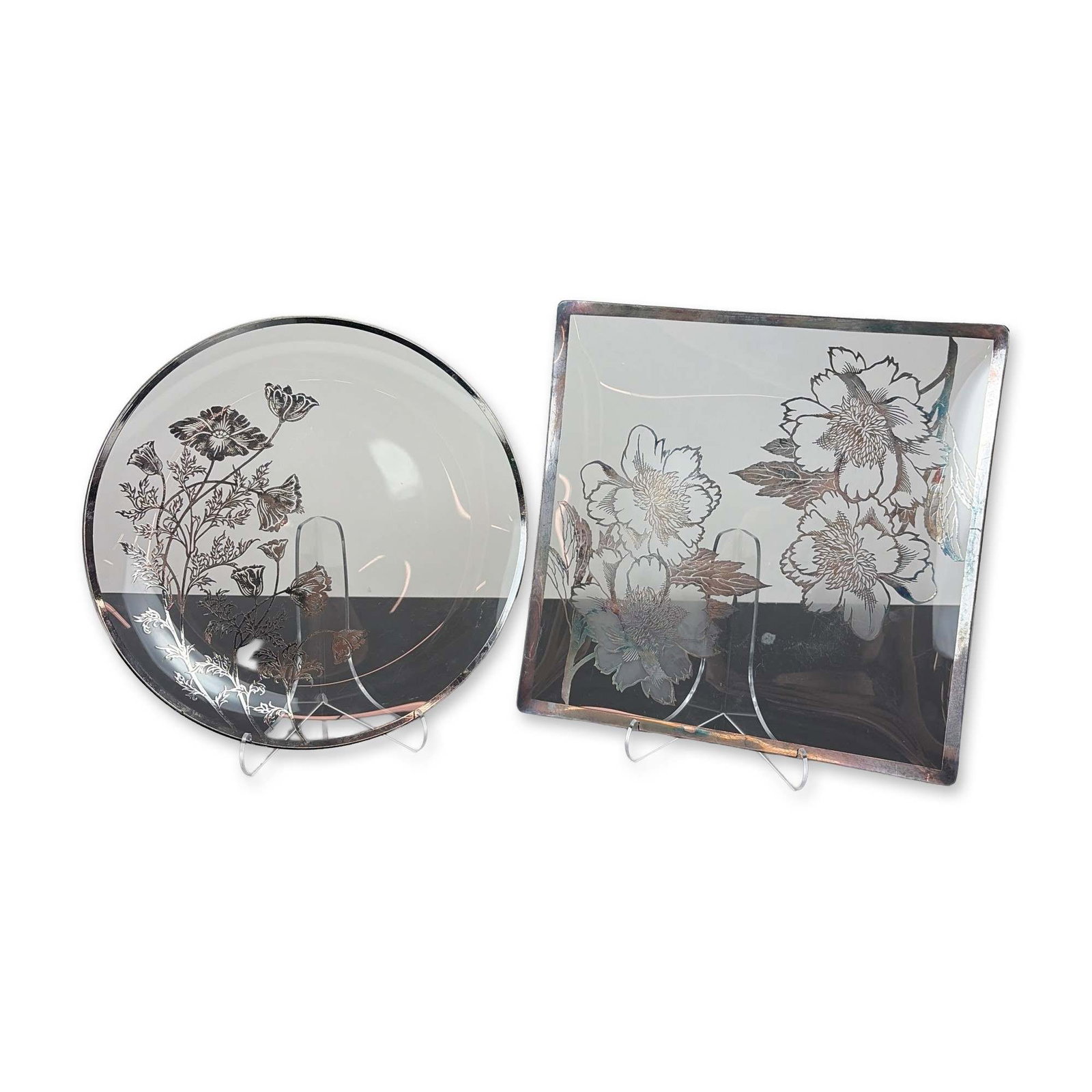 Two American Silver Overlay Glass Dishes: American mid-20th-century decorative glassware. Two pieces comprising a square tray and a round plate, each featuring clear glass bodies with silver-toned metal overlay motifs. The square tray depicts