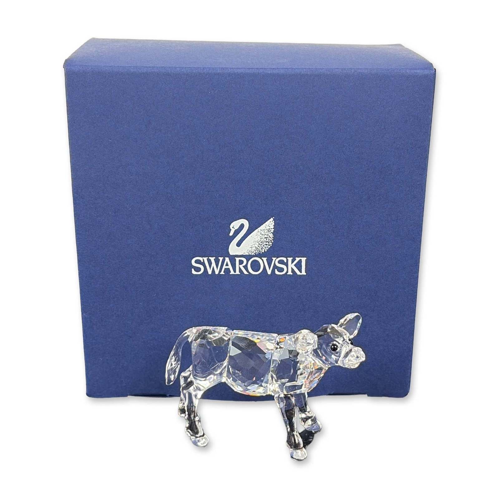 Swarovski Clear Crystal Calf Figurine: Swarovski faceted clear crystal figurine depicting a standing calf. The piece features jet-colored crystal eyes and faceted surfaces throughout the head, body, and legs. Bears etched Swarovski swan lo
