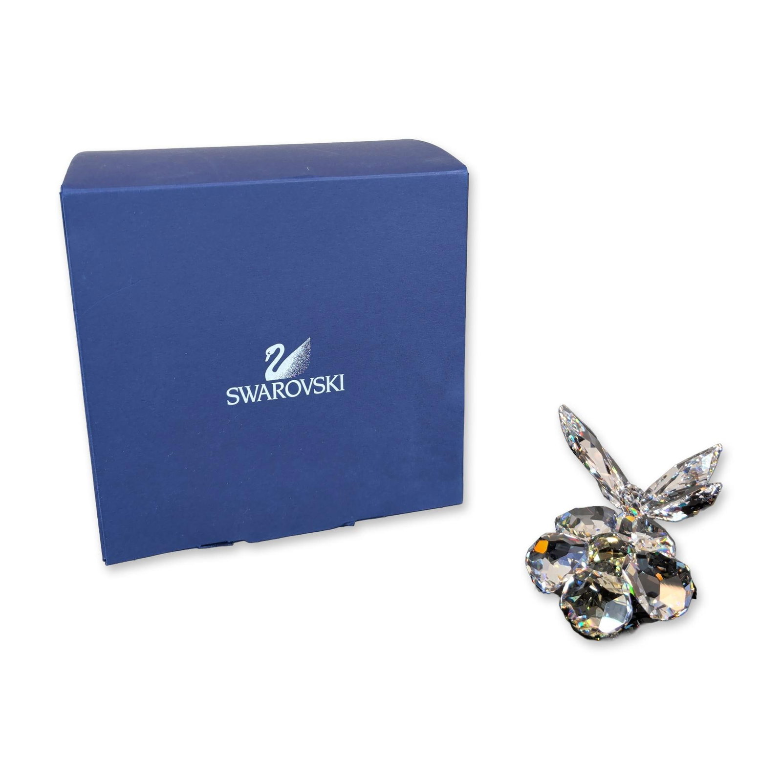 Swarovski Crystal Butterfly on Flower Figurine: Swarovski. Figurine in faceted clear lead crystal depicting a four-winged butterfly perched on a five-petaled flower. Features a laser-etched swan logo on the central flower facet. Accompanied by the 
