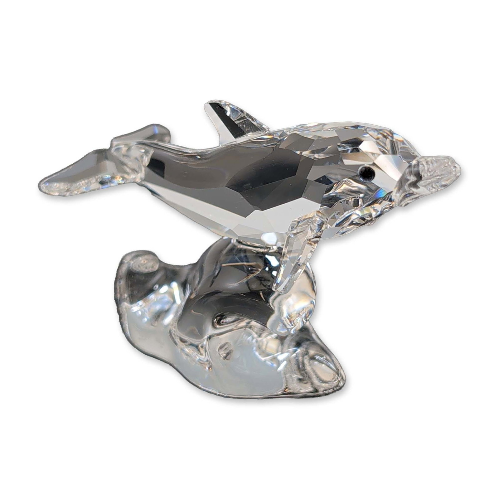 Swarovski Crystal Dolphin on Wave Figurine: Swarovski faceted lead crystal figurine depicting a dolphin leaping over a stylized wave from the Aquatic Worlds collection. The dolphin features a multi-faceted body with clear fins and tail, accente