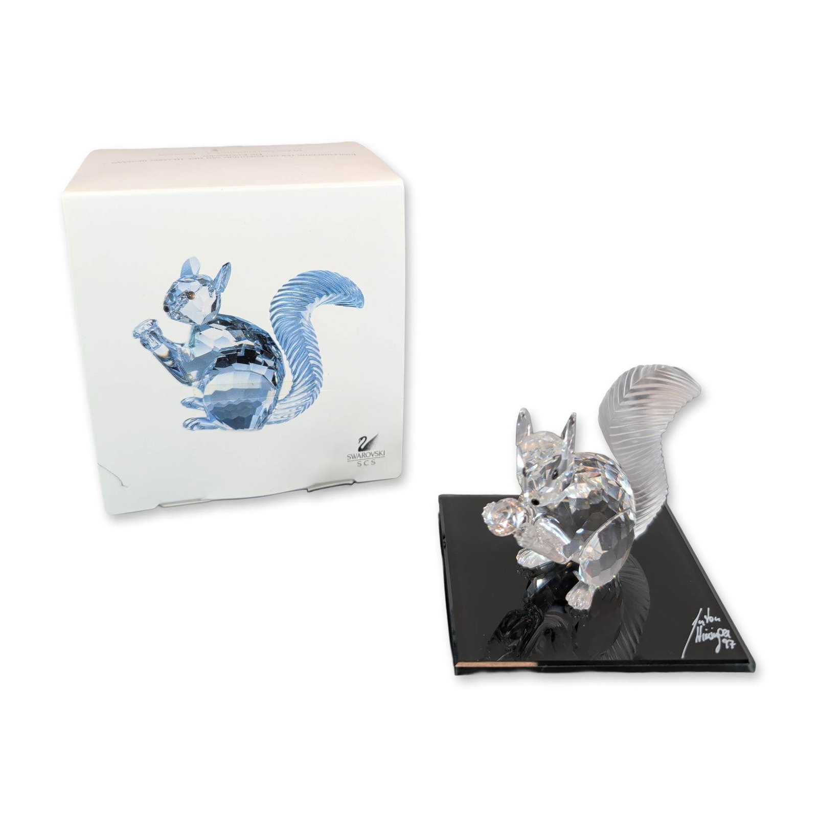 Swarovski SCS 10th Anniversary Crystal Squirrel Figurine with Mirror Display Base: Swarovski Crystal Society (SCS) tenth anniversary commemorative squirrel figurine in faceted clear crystal featuring a frosted textured tail. Designed by Anton Hirzinger for the society's 1987-1997 an