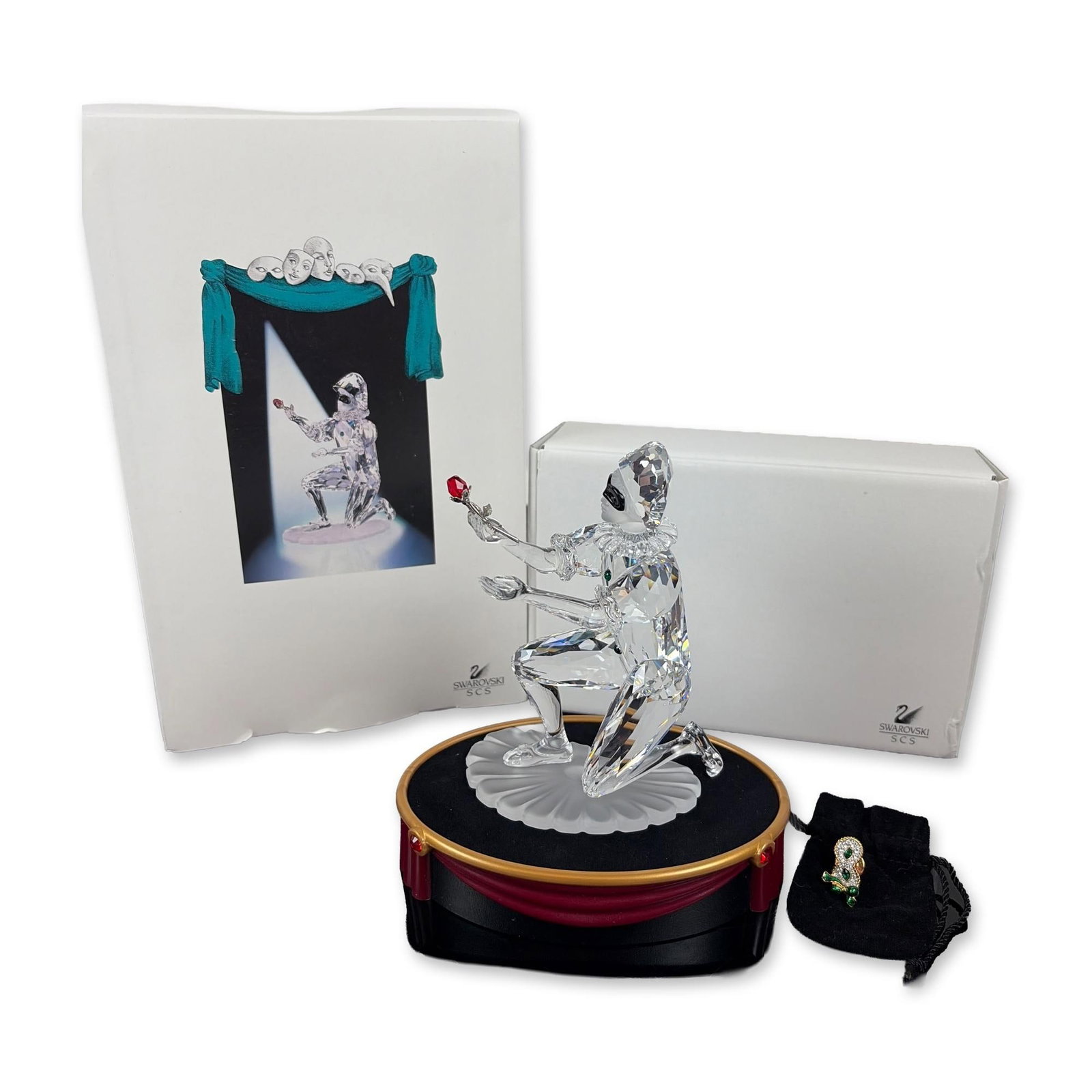 3pc Swarovski SCS 2001 Annual Edition Harlequin Crystal Figurine, Pin, and Base: This 3-piece set features a Swarovski figurine, pin, and base. Designed by Anton Hirzinger, it is the second release in the Masquerade trilogy. The clear faceted lead crystal figure is posed dynamical