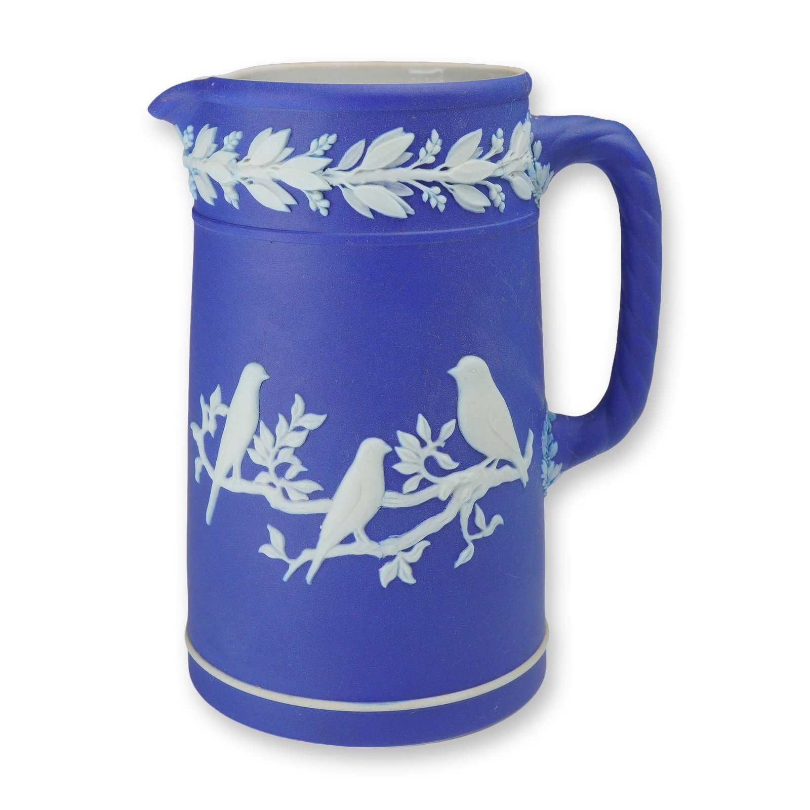 Wedgwood Dark Blue Jasperware Bird Pitcher: A Wedgwood dark blue jasperware jug featuring white applied bas-relief decoration. The cylindrical body is ornamented with three songbirds perched on leafy branches. A continuous laurel leaf wreath bo