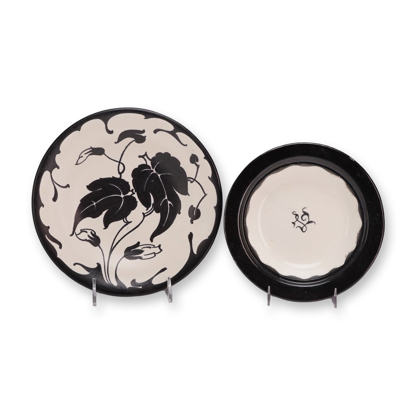 2pc Wedgwood and Fariet Schoonhoven Holland Pottery Plates: This lot features two pottery plates decorated with high-contrast black hand-painted motifs on a cream earthenware ground. The first piece is a cabinet plate featuring stylized foliate designs of larg