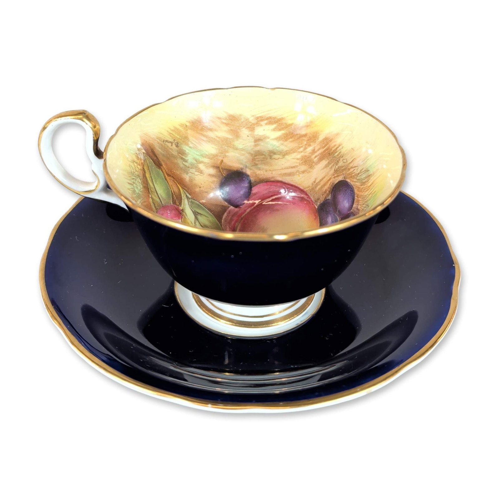 Aynsley England Orchard Fruit Porcelain Teacup and Saucer: Aynsley fine bone china teacup and saucer set in the Orchard Fruit pattern. The pedestal cup features a deep cobalt blue exterior with a scrolled, gilded handle and foot. The interior is decorated wit