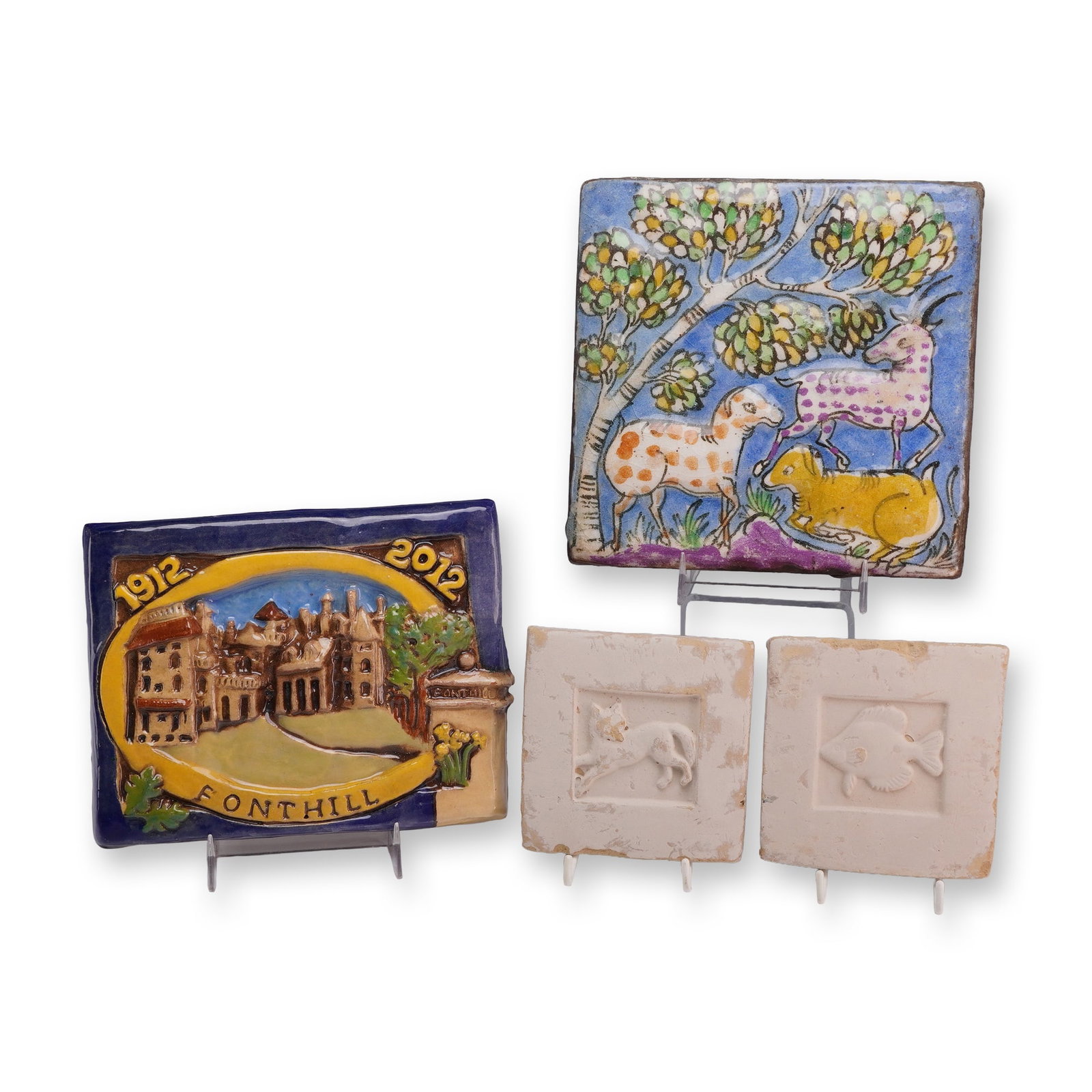 A Group of Four Ceramic Tiles Including a Moravian Pottery and Tile Works and Fonthill Centennial: This collection consists of four decorative ceramic tiles. The primary piece is a rectangular polychrome relief-molded earthenware plaque which features a central depiction of Fonthill Castle in a