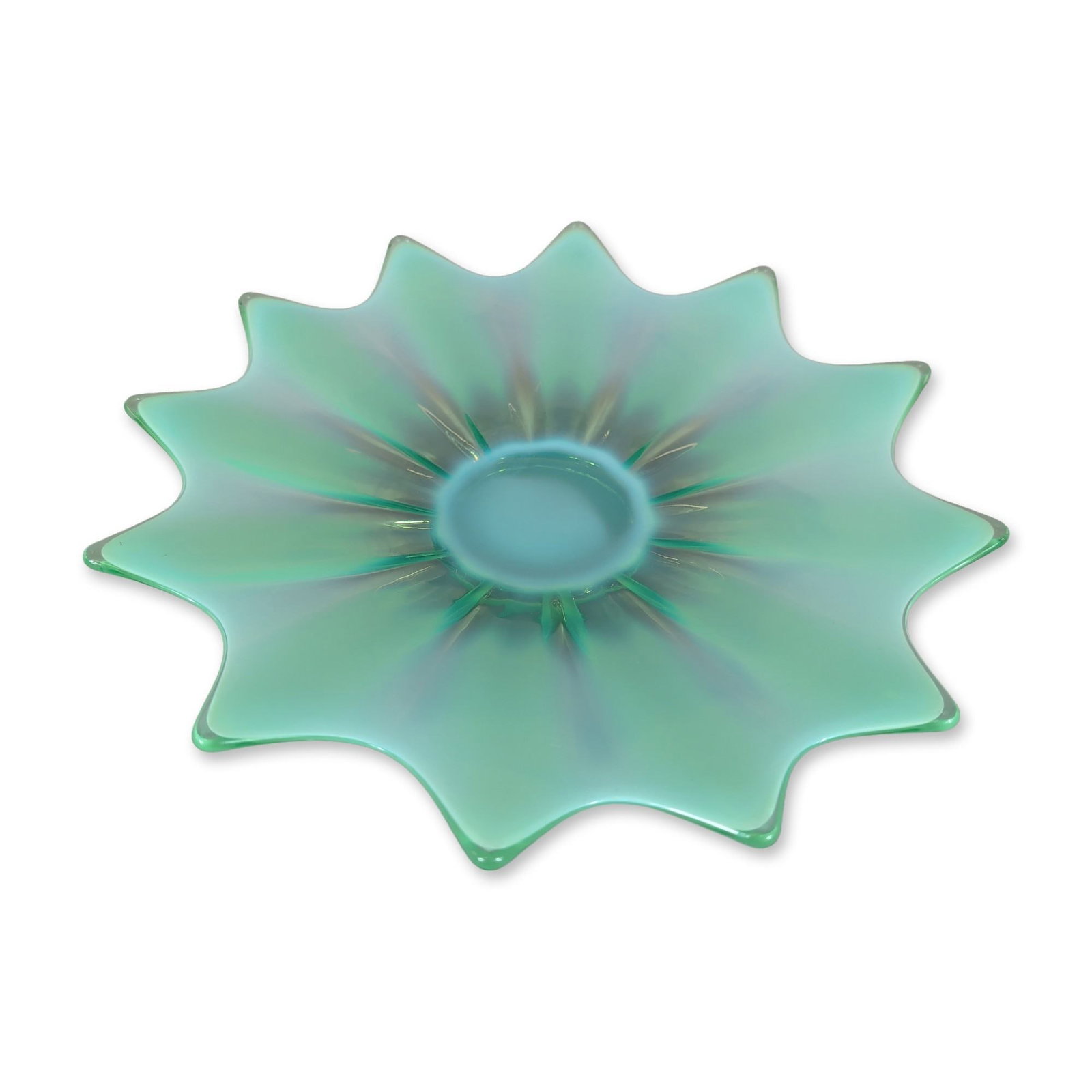 Fostoria Heirloom Green Glass Bowl: Fostoria, Heirloom pattern. Mid-20th century American shallow bowl in green opalescent pressed glass, featuring a twelve-point starburst design with radiating ribs. The translucent opalescence is conc