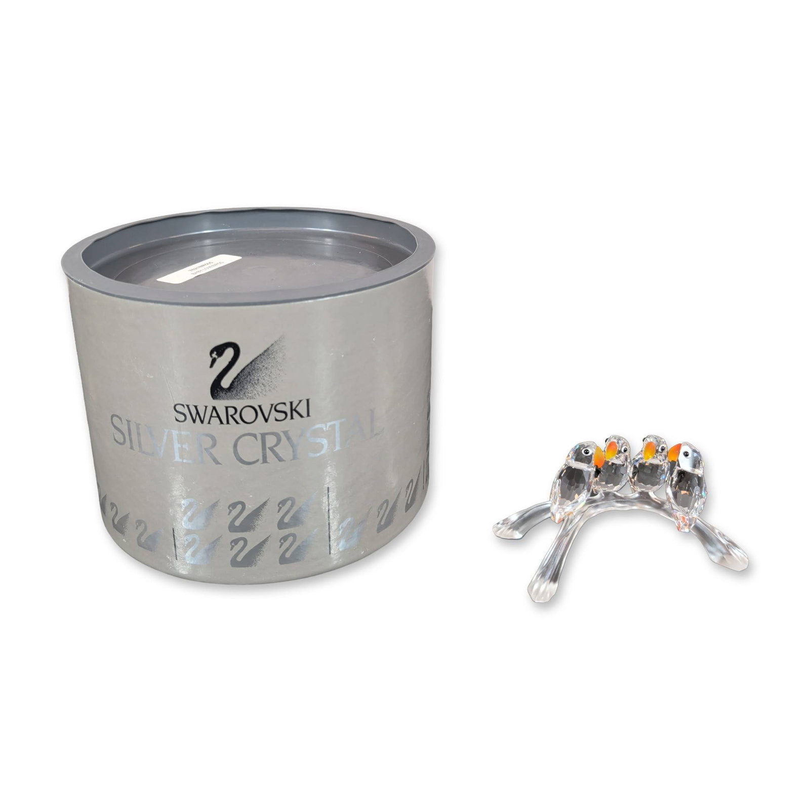 Swarovski Crystal Baby Lovebirds Figurine: Swarovski Silver Crystal figurine depicting four birds perched on an arched branch, featuring faceted clear lead crystal bird bodies with yellow and orange beaks and black dot eyes. The group is mount