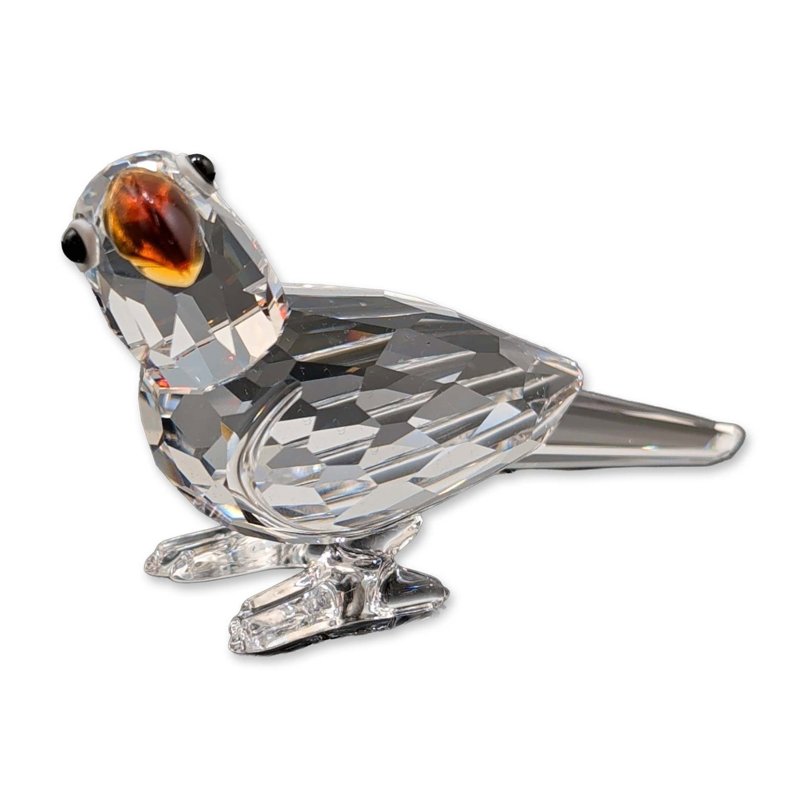 Swarovski Crystal Figurine, Parrot: Swarovski crystal figurine depicting a parrot in a perched, leaning pose. The piece is constructed from clear faceted lead crystal with an amber-tangerine colored crystal beak and small black eyes. Fe