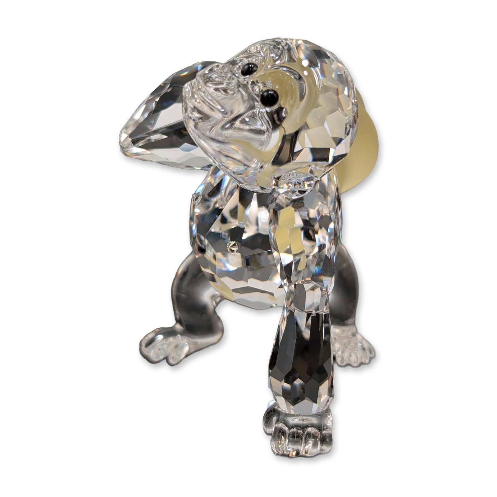 Swarovski Crystal Figurine, Young Gorilla: Swarovski figurine in faceted clear crystal, black crystal, and yellow frosted crystal, depicting a young gorilla in a crouching pose holding a banana bunch. Part of the Rare Encounters collection. In