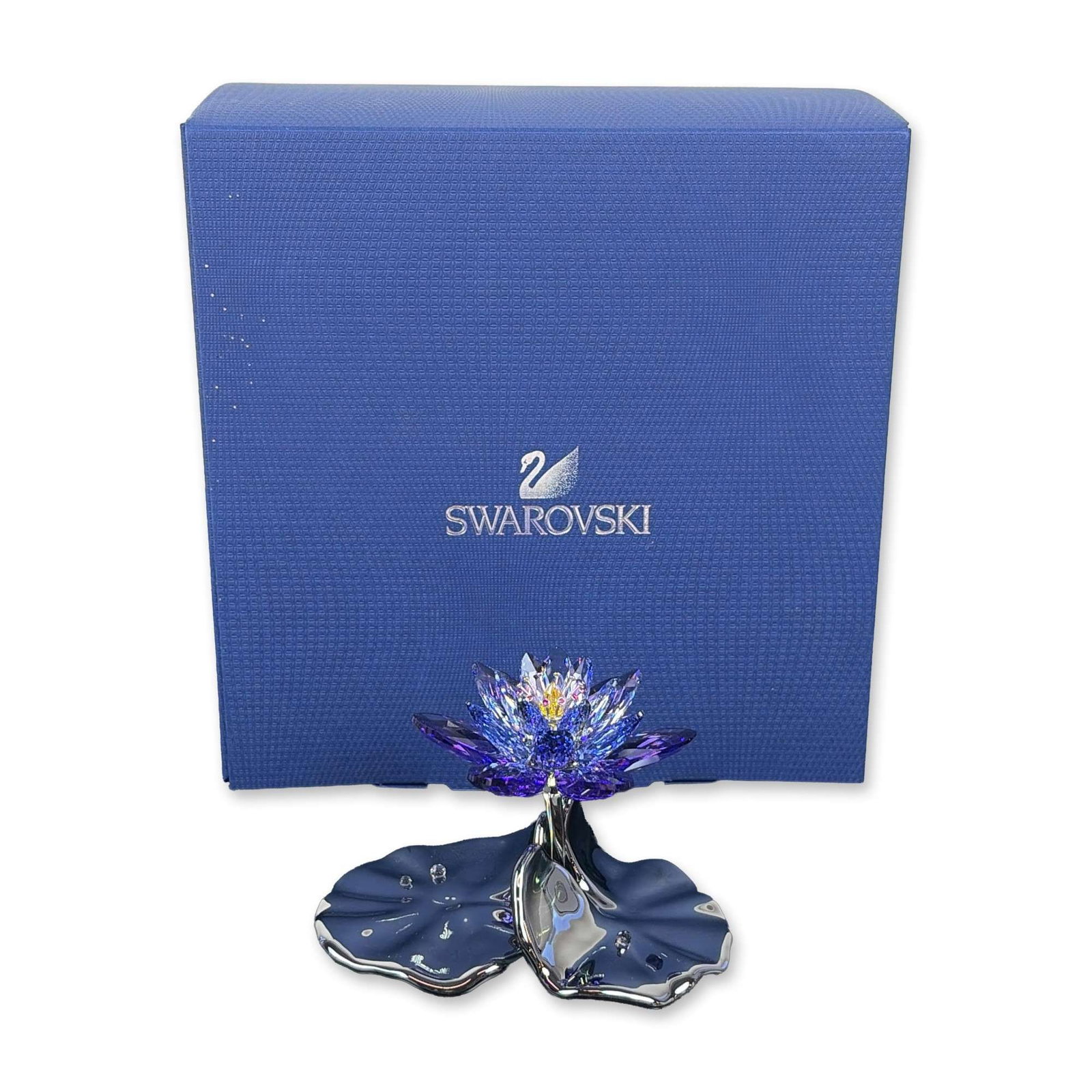 Swarovski Crystal Waterlily Blue Violet Figurine: Swarovski Waterlily is a decorative piece featuring a blooming waterlily with multi-tiered, faceted lead crystal petals in shades of blue and violet, encircling a bright yellow crystal stamen. The flo