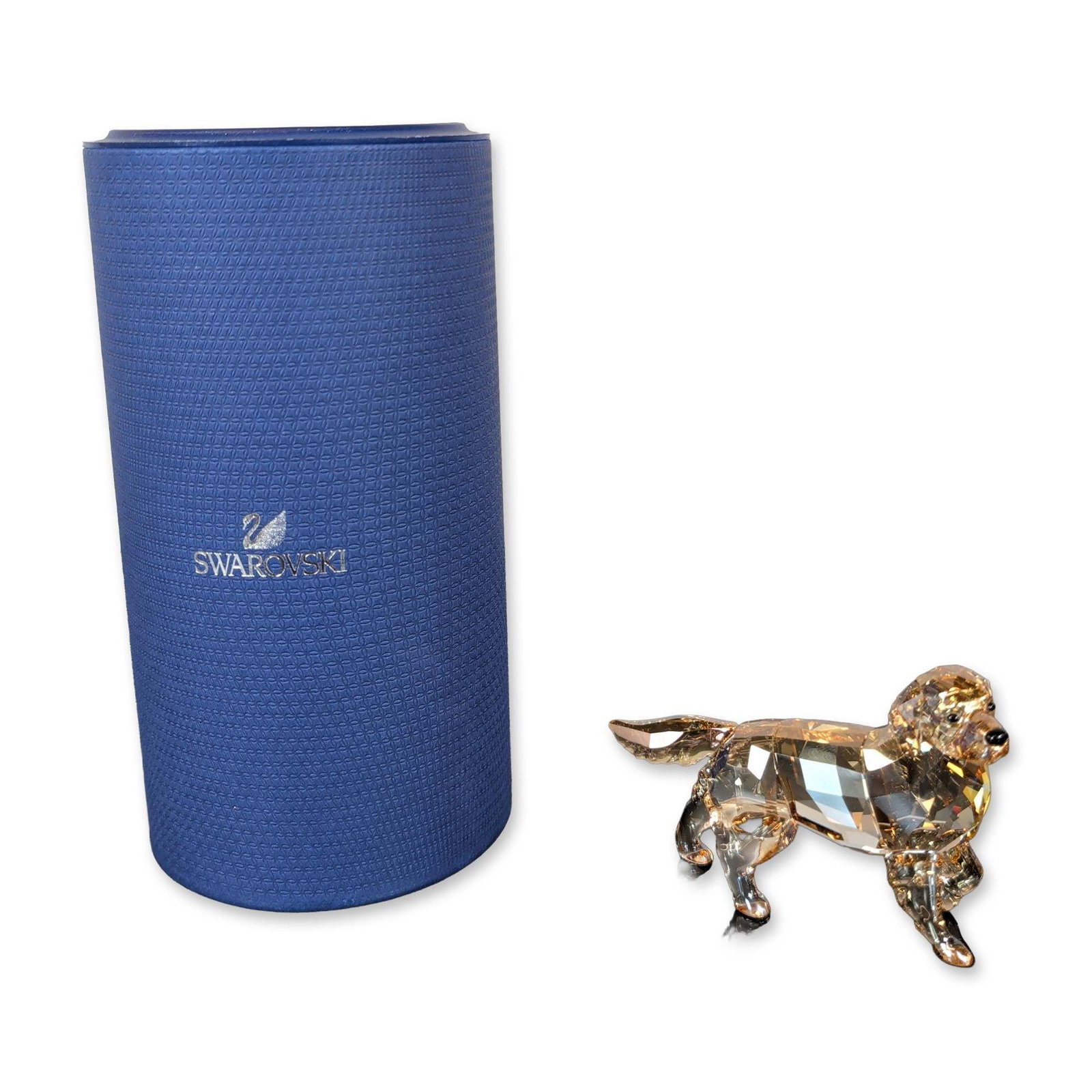Swarovski Golden Retriever Mother Figurine: Golden Retriever Mother figurine crafted in a golden amber crystal with dark faceted crystal eyes and nose. The Swarovski swan logo is etched on the underside of the piece. Includes the original blue 