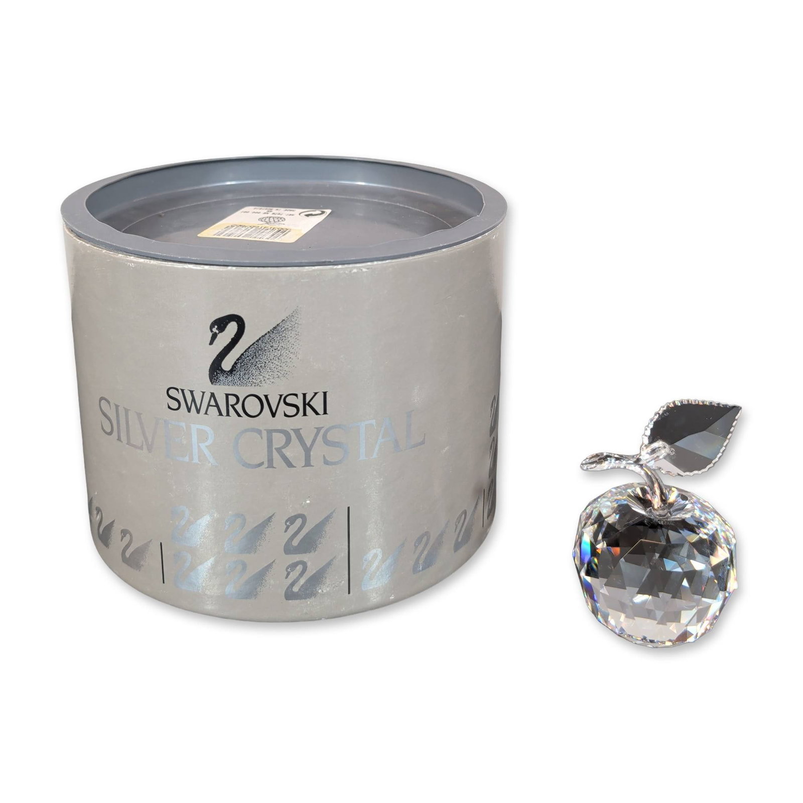Swarovski Silver Crystal Apple Figurine: Swarovski Apple figurine in faceted lead crystal featuring a faceted globular body, a smooth curved stem, and a single faceted leaf. The underside of the leaf bears an etched stylized swan logo. Accom