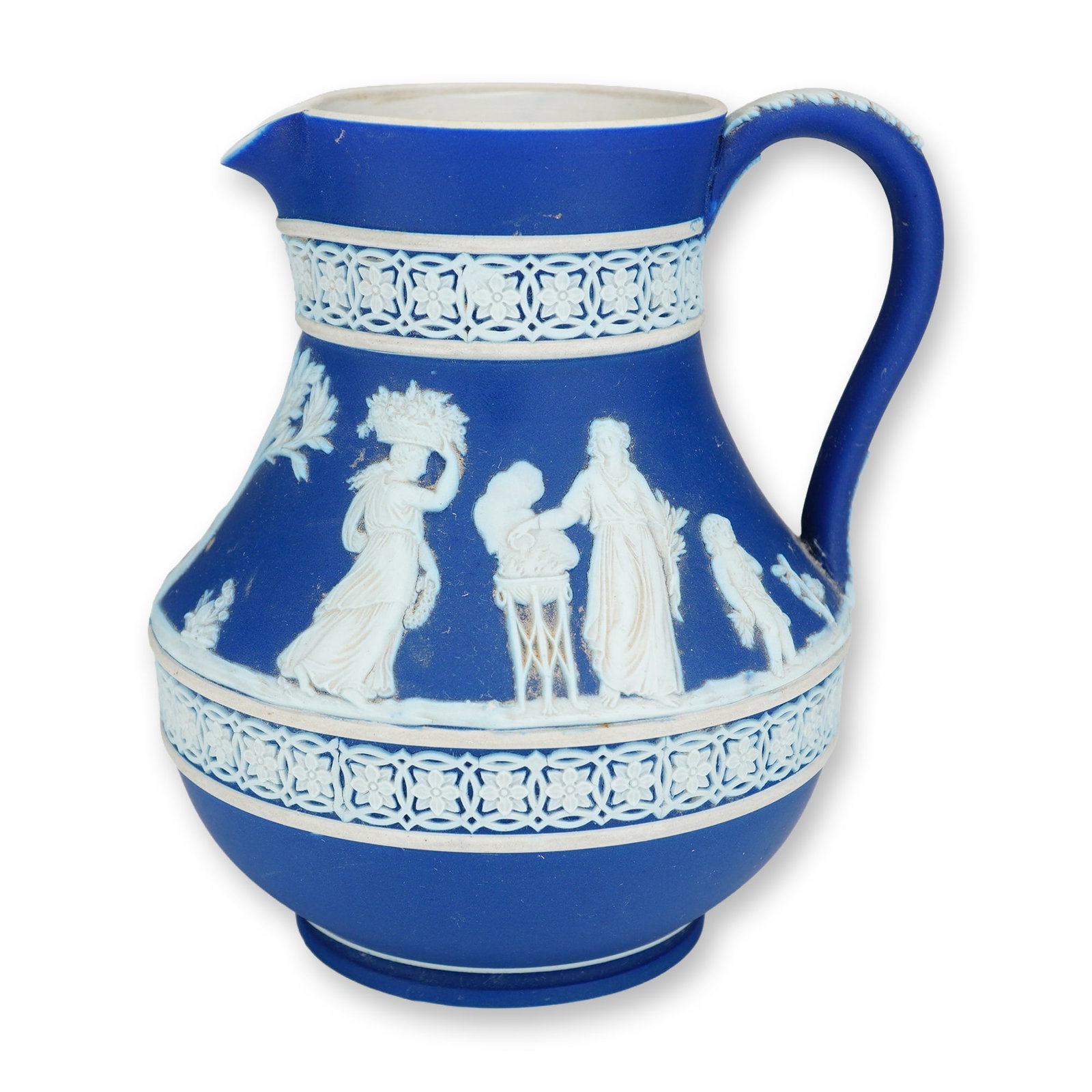 Wedgwood Dark Blue Jasperware Etruscan Pitcher: A Wedgwood dark blue jasperware pitcher featuring a bulbous Etruscan-style body, a high loop handle, and a pinched pouring spout. The exterior is decorated with sprigged white relief ornamentation aga