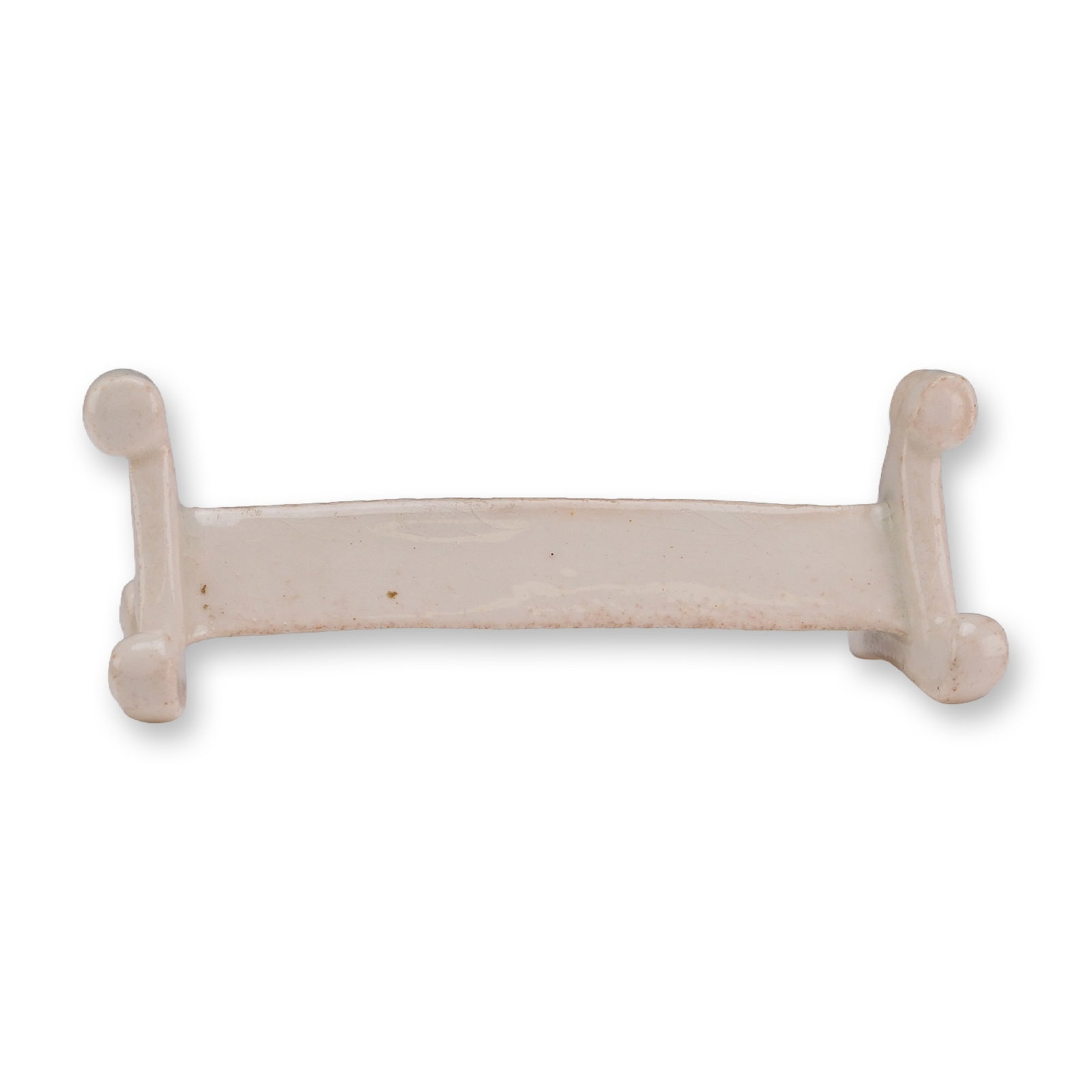 Wedgwood White Glazed Ceramic Knife Rest: This white glazed ceramic knife rest features a central shaft with molded feet at each end. These feet are decorated with relief-molded scroll and foliate designs. The piece is finished in an opaque