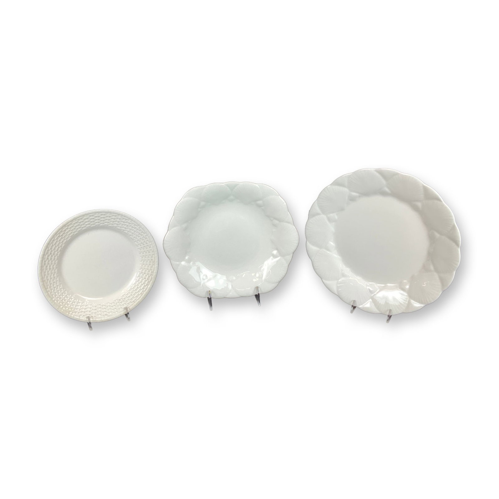Three Wedgwood Bone China Plates in Oceanside and Nantucket Patterns: A group of three white bone china plates manufactured by Wedgwood in England. The collection includes pieces from two distinct relief-molded patterns. Two plates are in the Oceanside pattern, which