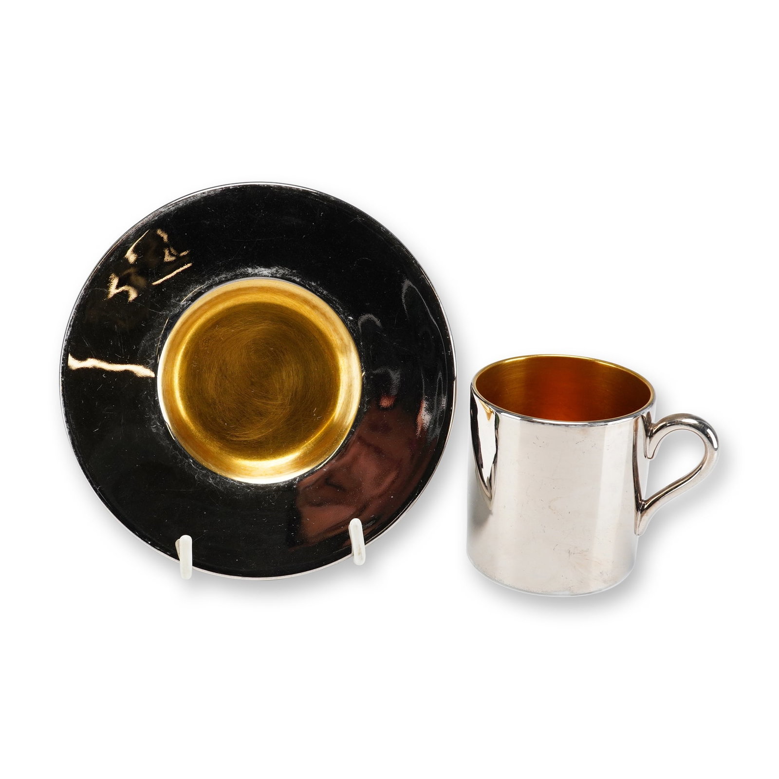 Wedgwood Silver and Gold Metallic Luster Porcelain Demitasse Cup and Saucer: A two-piece demitasse cup and saucer set manufactured by Wedgwood in England. The set is constructed of white porcelain finished with contrasting metallic luster glazes. The straight-sided cup