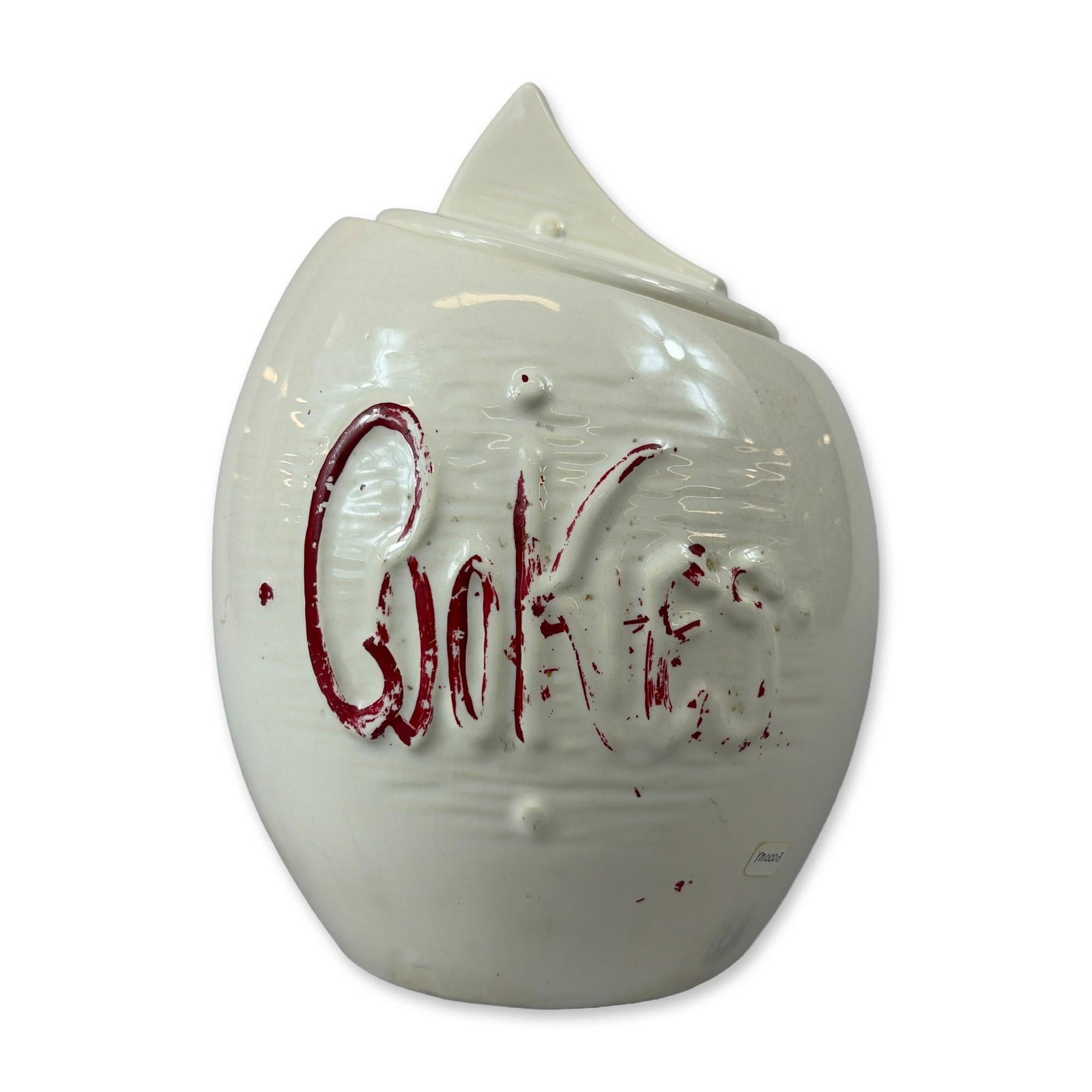 McCoy Ceramic Cookie Jar: Ceramic cookie jar in white glazed earthenware, featuring a matching lid with a stylized wedge handle and molded cursive Cookies lettering highlighted with red cold paint. The underside of the base sh