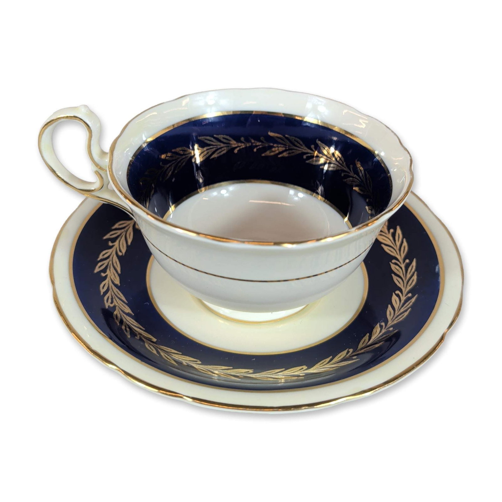 Aynsley Cobalt Blue and Gold Cup and Saucer: Aynsley, England. Bone china cup and saucer set featuring a wide cobalt blue border decorated with gilded laurel leaf scrolls. The cup is designed with a scalloped rim, pedestal foot, and looped gilde