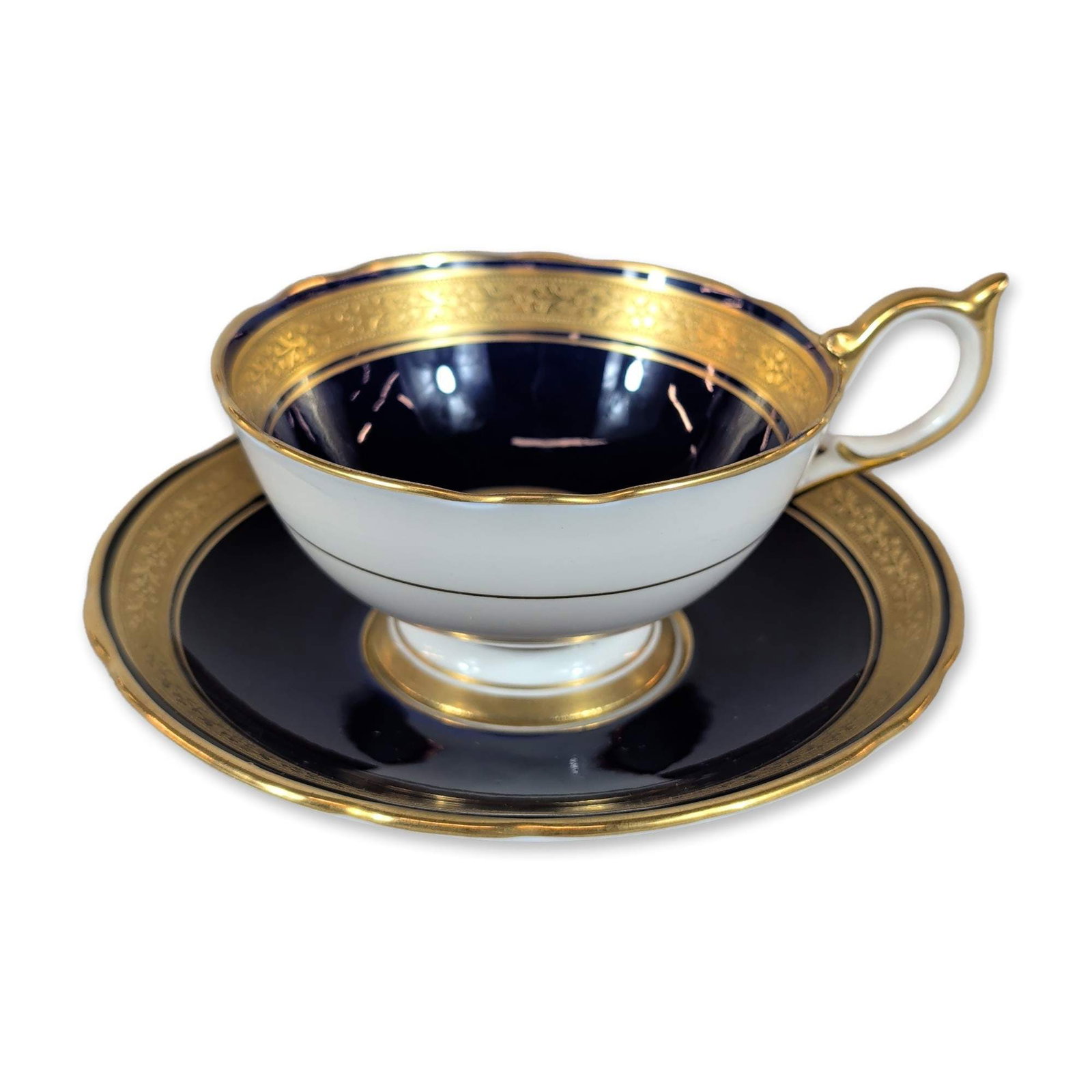 Aynsley England Cobalt Blue Gilt Teacup and Saucer: Aynsley, England. Teacup and saucer in fine bone china, featuring a deep cobalt blue glaze and wide acid-etched style gilded borders with repeating floral swags and classical scrollwork. The footed te