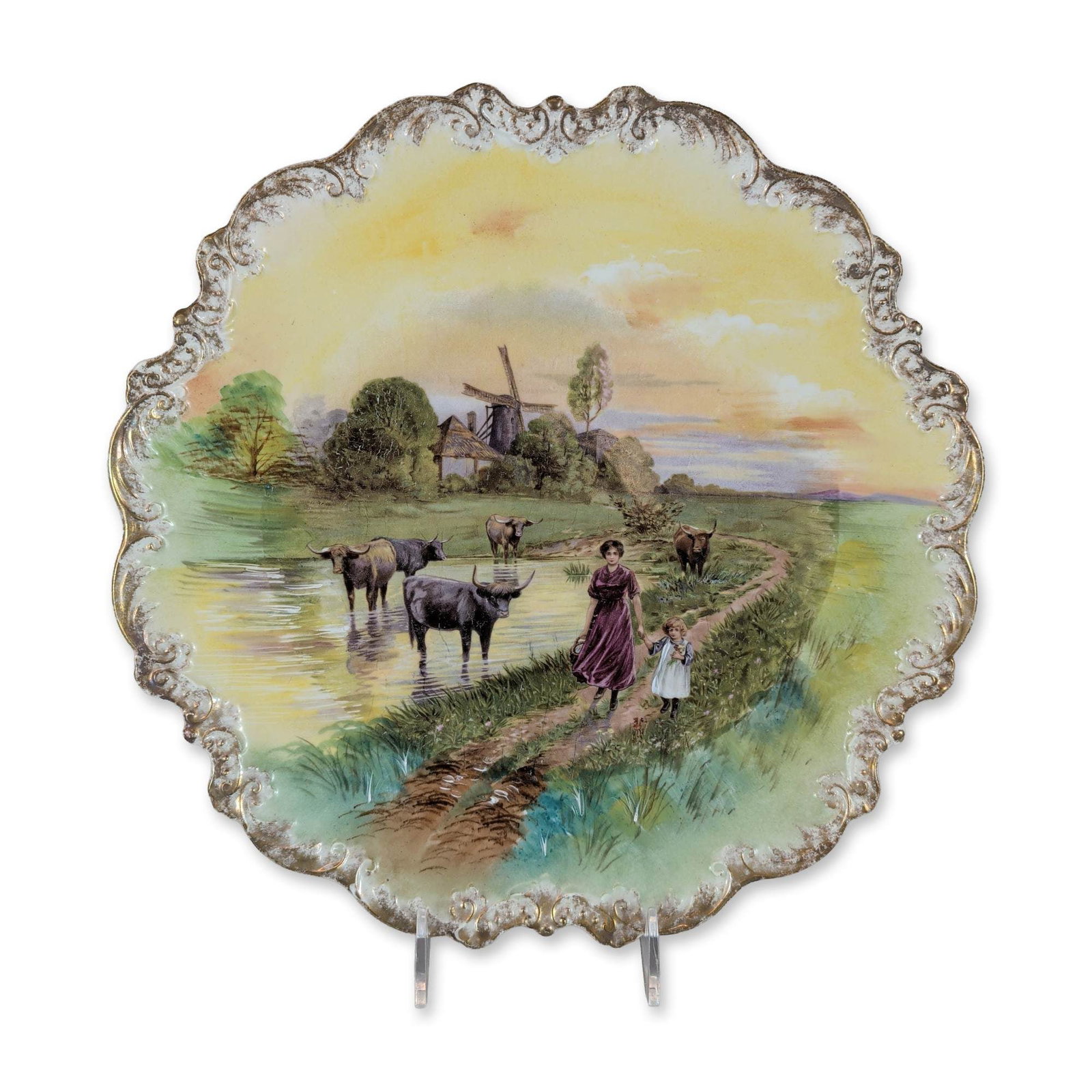 Limoges France Hand-Painted Porcelain Scenic Plate: Limoges, France hand-painted porcelain cabinet plate featuring a pastoral Dutch-style landscape scene. The composition depicts a woman and child along a riverbank with cattle wading in the water, set 