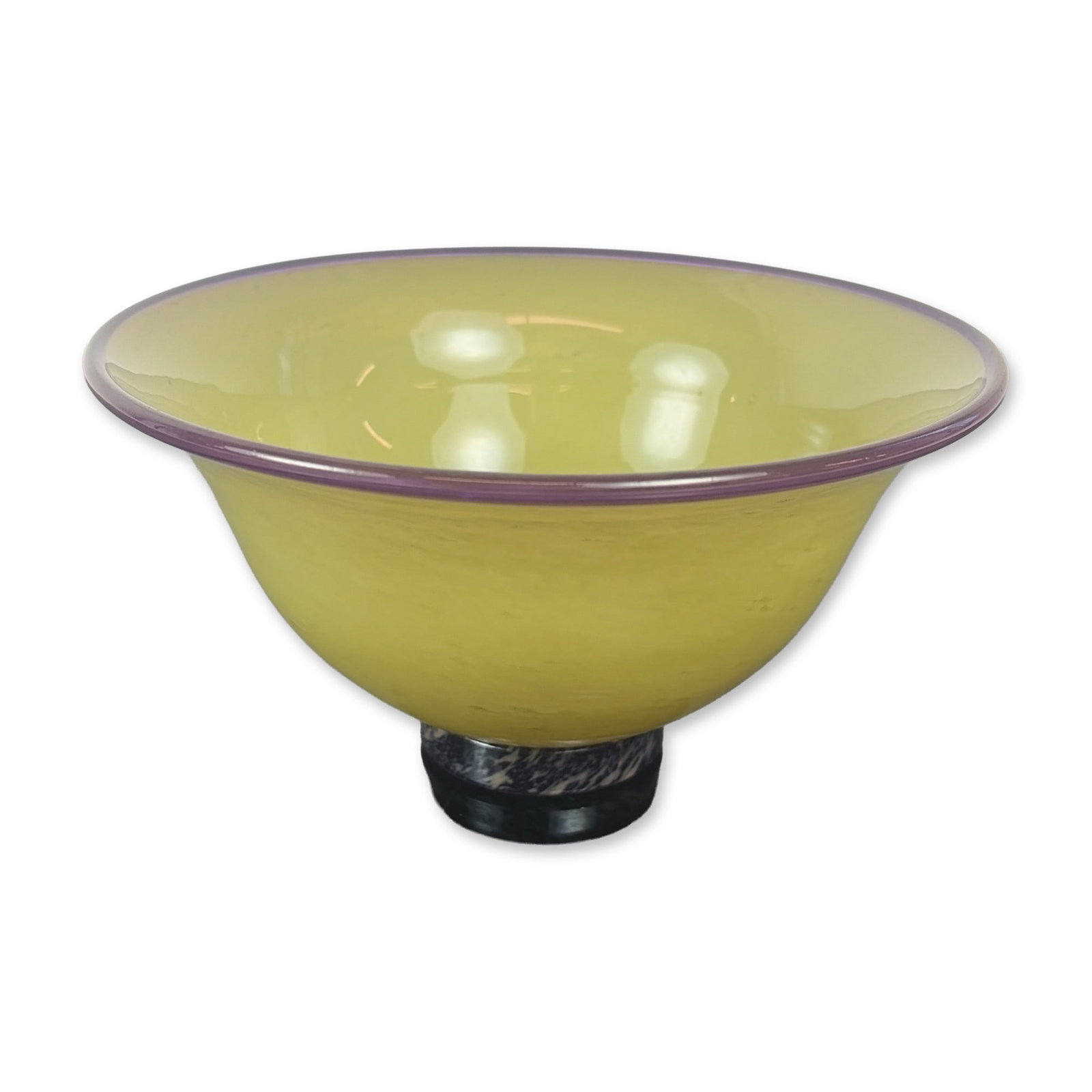 Liz Marx Studio Glass Bowl: Hand-blown glass in a wide flared form, featuring a chartreuse seeded body with an applied amethyst purple rim. The bowl sits on a small integrated cylindrical foot with a marbled finish in dark blue,