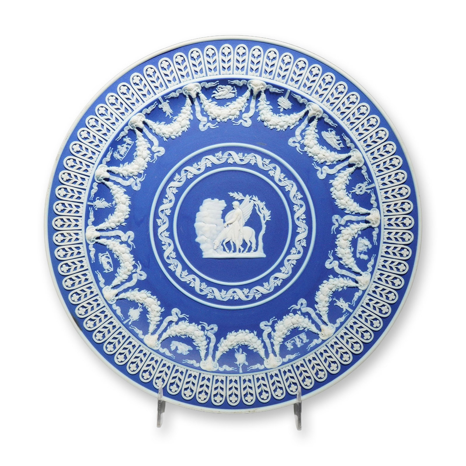 Wedgwood Blue and White Jasperware Trophy Plate Featuring Bellerophon and Pegasus: A Wedgwood blue jasperware ornate dish or trophy plate featuring intricate white relief decoration. The central circular medallion depicts the classical scene of Bellerophon mounted on the winged hors
