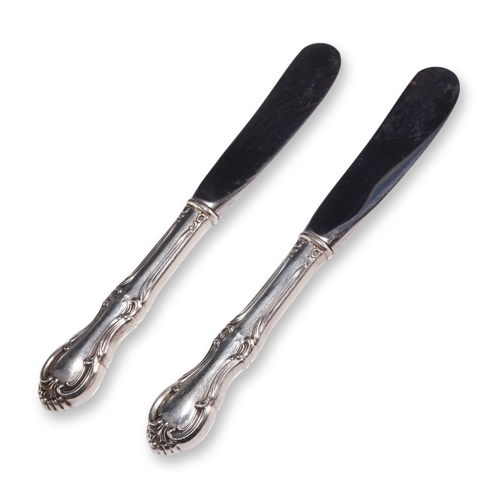 Pair of International Sterling Butter Spreaders, Joan of Arc: Pair of American sterling silver hollow-handled butter spreaders in the Joan of Arc pattern by International Silver Company. Each spreader features an ornate Rococo Revival style design with scrolled 