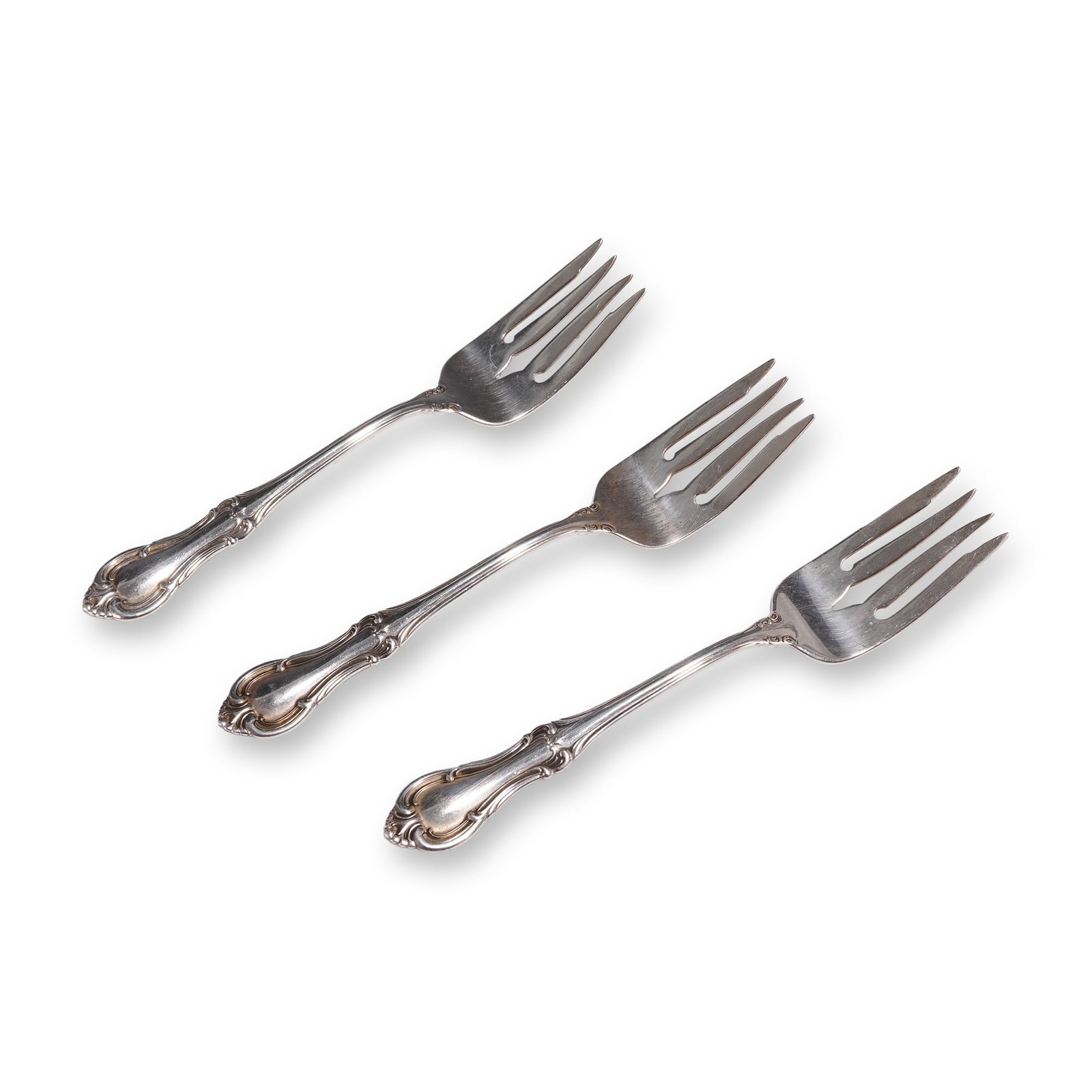 Three International Sterling Salad Forks, Joan of Arc: Three sterling silver salad forks in the Joan of Arc pattern by International Silver Company. Each fork features a French Provincial style handle with scrolling shell and floral motifs. The reverse of
