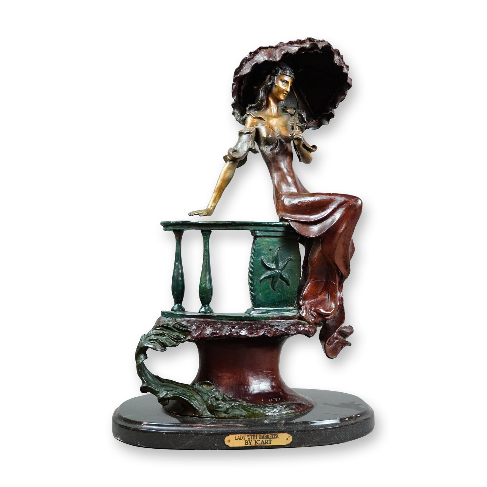 Louis Icart (French, 1888-1950), Lady with Umbrella Bronze: After Louis Icart. Art Deco style polychrome patinated bronze sculpture titled Lady with Umbrella, depicting an elegantly dressed woman with a ruffled parasol seated upon a balustrade. The figure is f