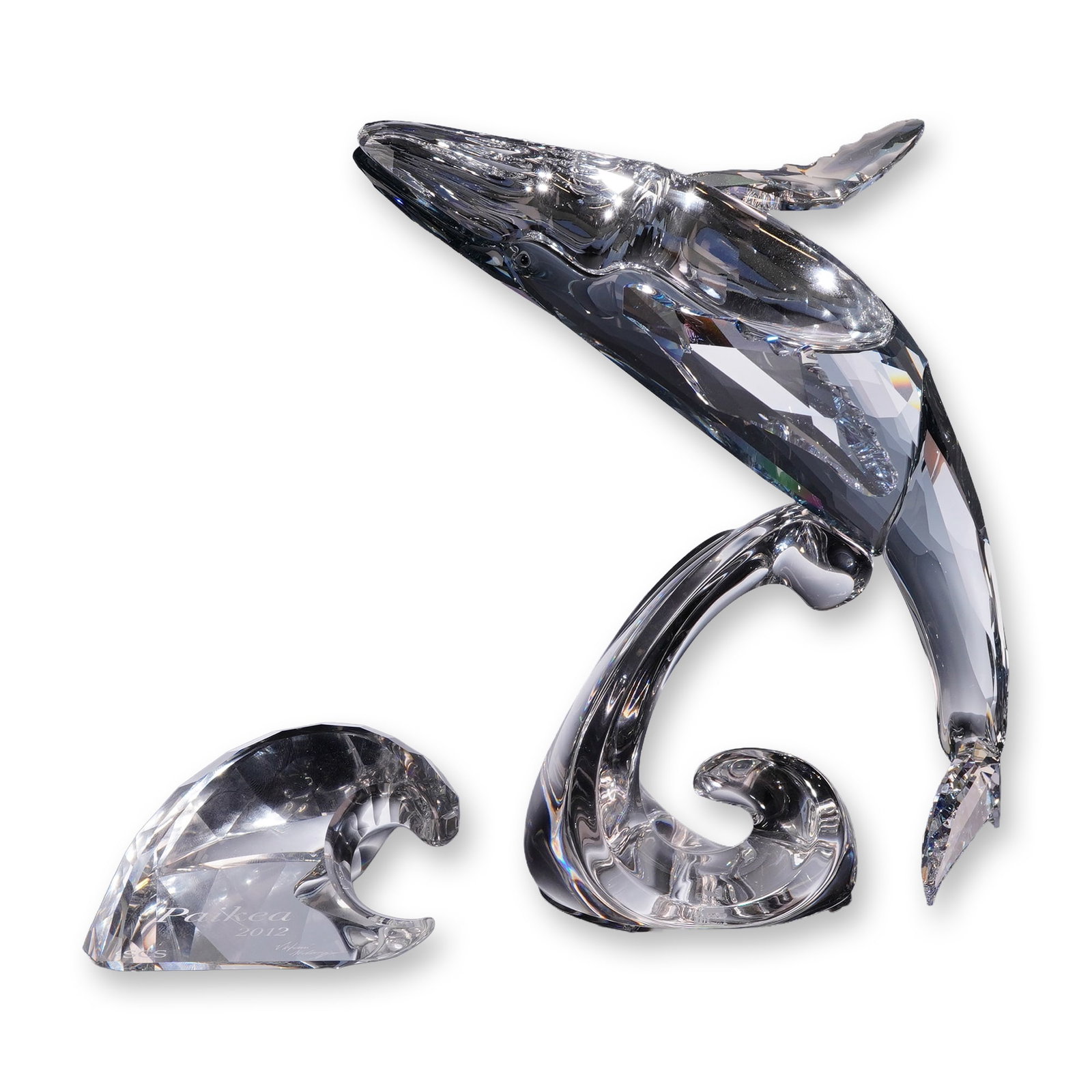 Swarovski 2012 SCS Paikea Humpback Whale Figurine: Swarovski. 2012 SCS Annual Edition humpback whale figurine titled Paikea, model 1095228, in faceted clear lead crystal. Featuring a breaching whale form mounted on a swirling water-motif base. Accompa