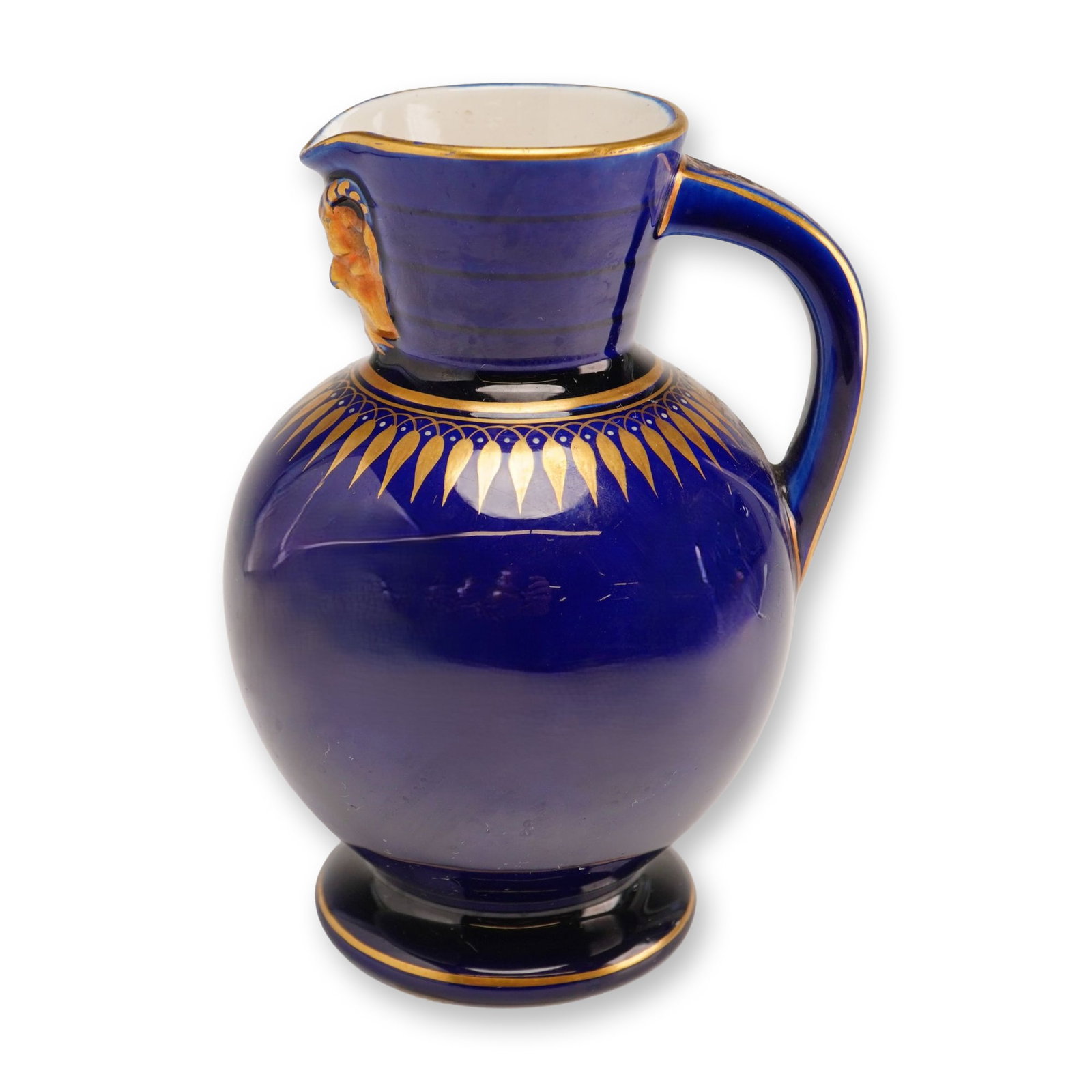 Wedgwood Cobalt and Gilt Doric Jug with Satyr Mask: A Wedgwood earthenware jug of the Doric shape, featuring a bulbous body, flared neck, and a high-set ear-shaped handle. The piece is finished in a deep cobalt blue glaze and decorated with hand-applie