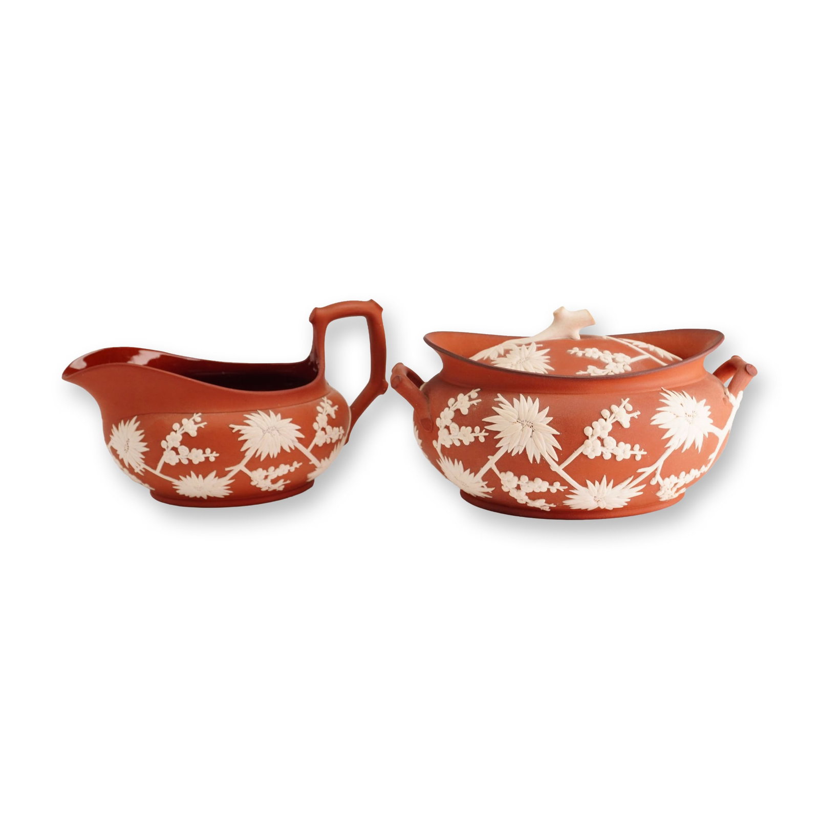 2pc Wedgwood Rosso Antico Lidded Dish and Saucer, Prunus ca. 1810: A two-piece Wedgwood Rosso Antico stoneware set featuring white sprigged prunus decoration, dating to approximately 1810. This lot consists of a lidded oval dish and a saucer-form creamer. The lidded