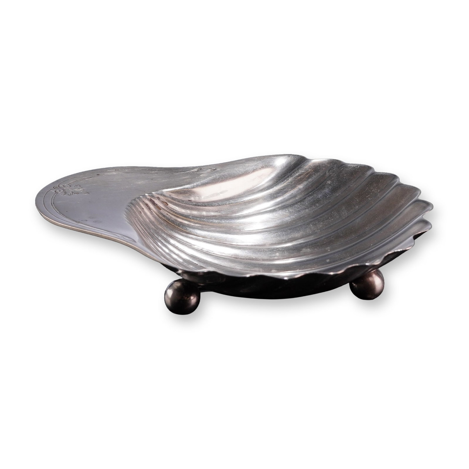 Sterling Silver Shell Form Footed Dish: Sterling silver footed dish in a clamshell form, featuring a fluted and scalloped body supported by three spherical ball feet. The handle extension is decorated with an engraved fleur-de-lis motif. St