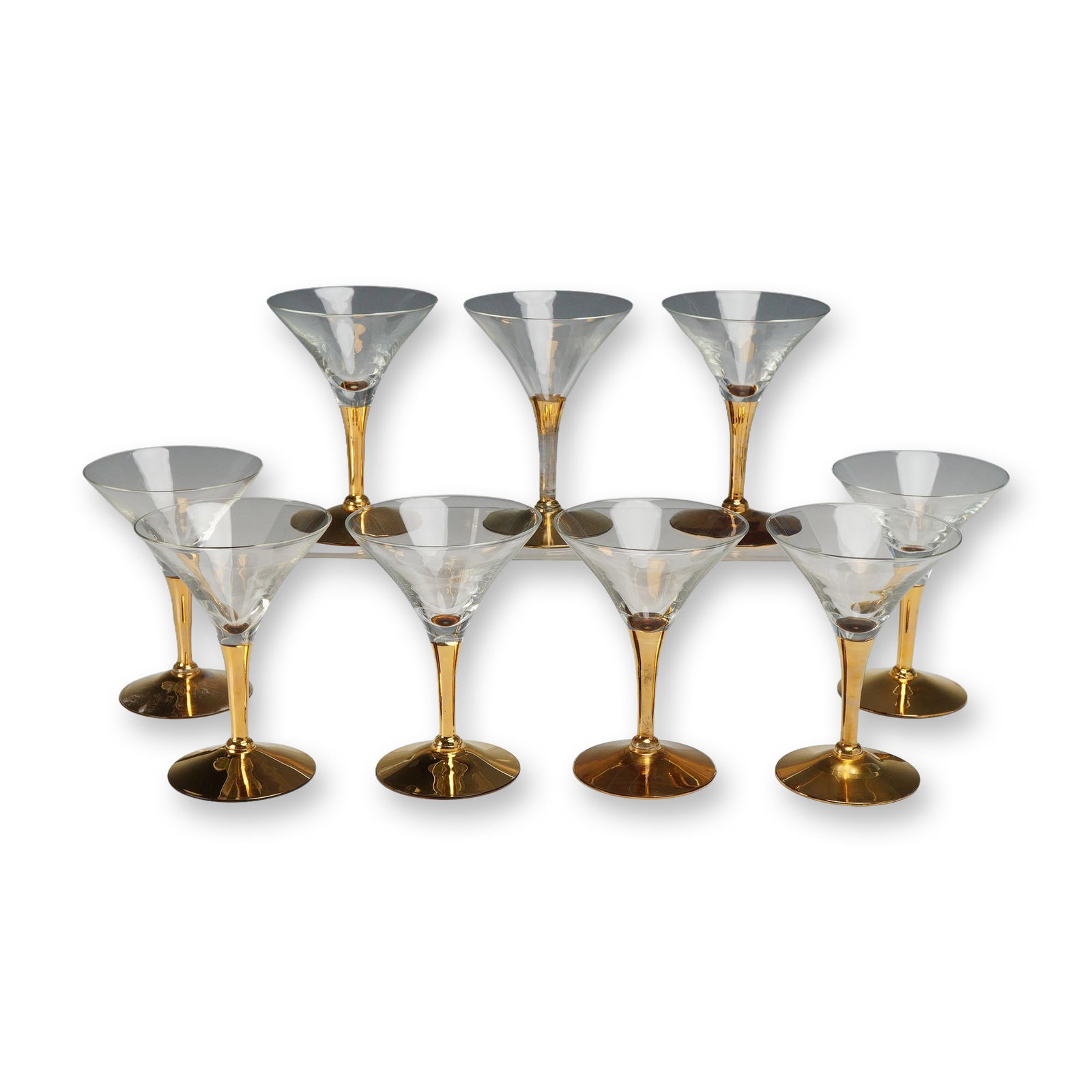 Set of Nine Gilt Stem Martini Glasses: Mid-century modern martini glasses featuring clear glass conical bowls. Each glass is supported by a flared stem and matching circular foot, finished with a decorative gold-washed gilt treatment. Dime