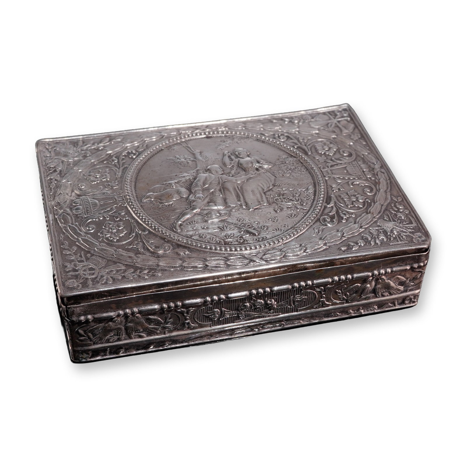 German 800 Silver Repousse Box, Romantic Scene in Relief: German, late 19th or early 20th century. Rectangular box in .800 silver, featuring a raised relief romantic scene on the lid. The central circular medallion depicts a pastoral couple seated beneath a 