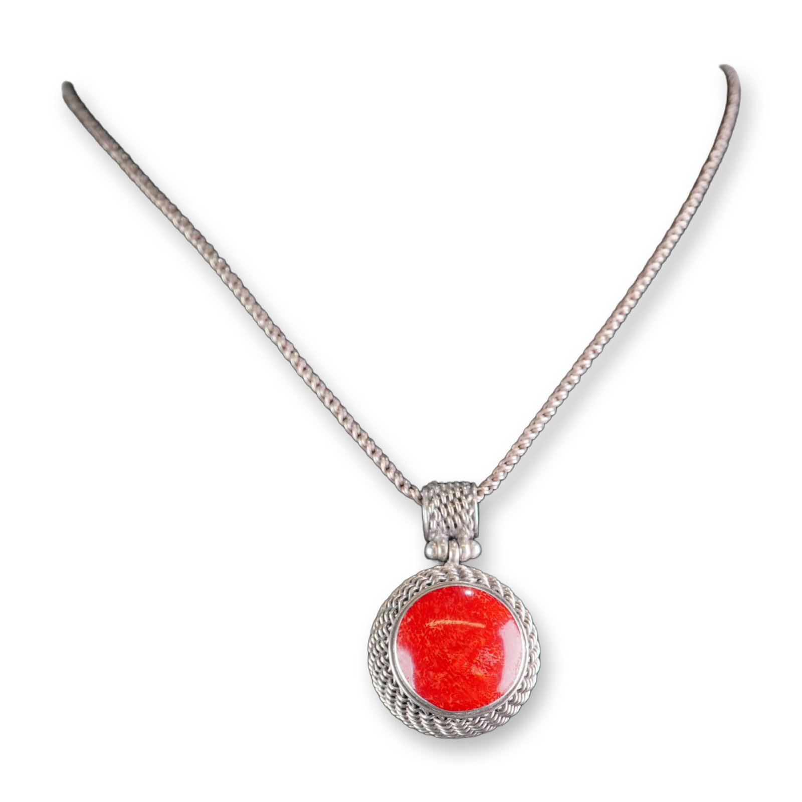 Sterling Silver Red Coral Pendant Necklace: Artisan sterling silver pendant necklace featuring a large circular red coral cabochon. The stone is bezel-set within a decorative woven silver wire mesh frame with an open-work back. The pendant is s