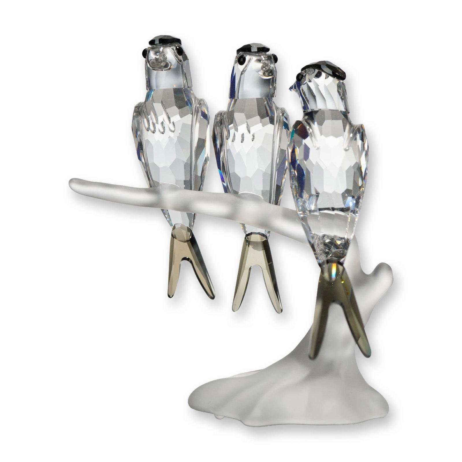 Swarovski Crystal Figurine, Swallows: Figurine in faceted clear lead crystal depicting three swallows on a shared branch. The birds feature jet crystal eyes and smoky-toned accents to the crown and tail feathers. The branch base is execut