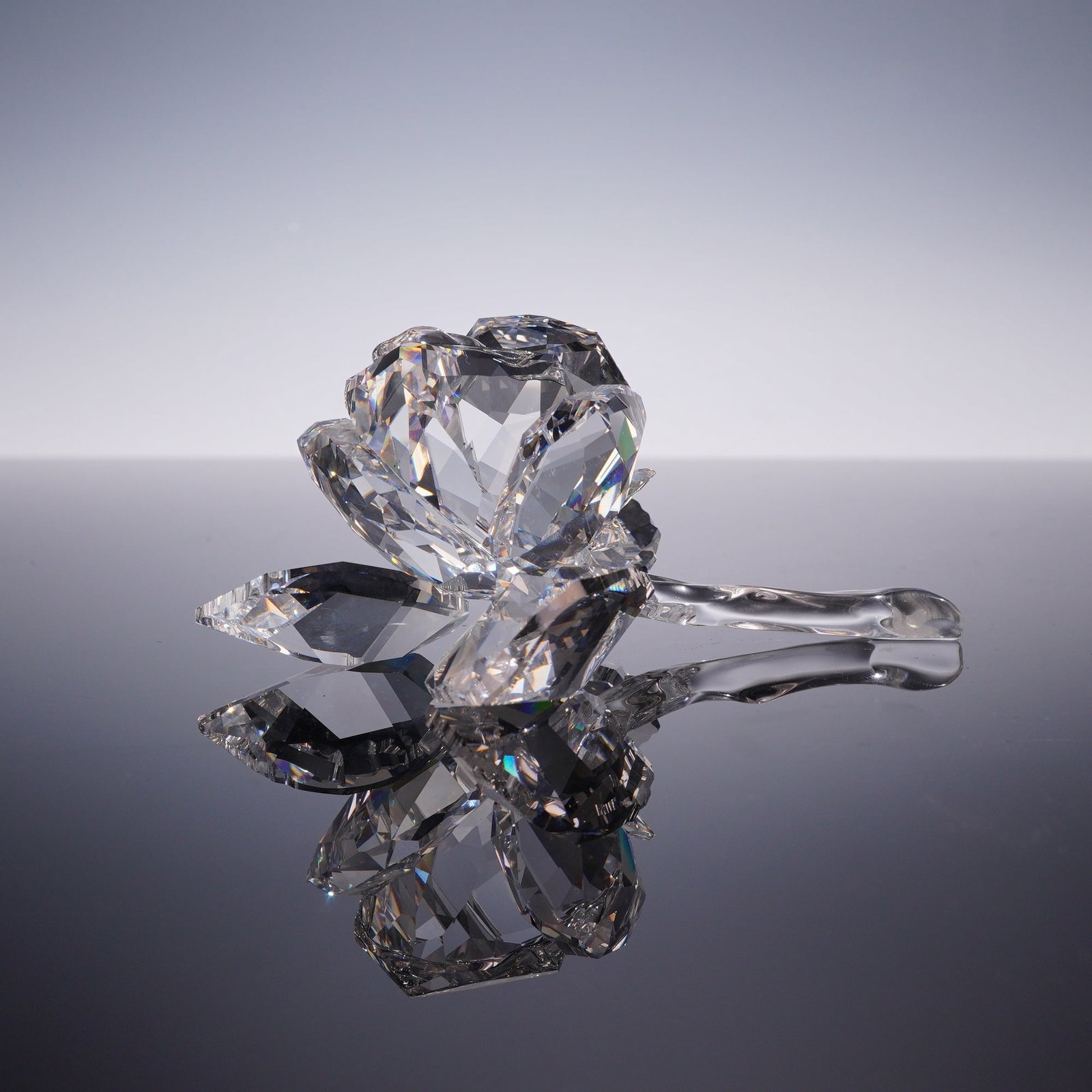 Swarovski Crystal Figurine, Rose Blossom: Rose blossom figurine in faceted clear crystal, featuring a detailed rose head in bloom attached to a smooth curved stem with three faceted leaves. Marked with an acid-etched Swarovski swan logo and c
