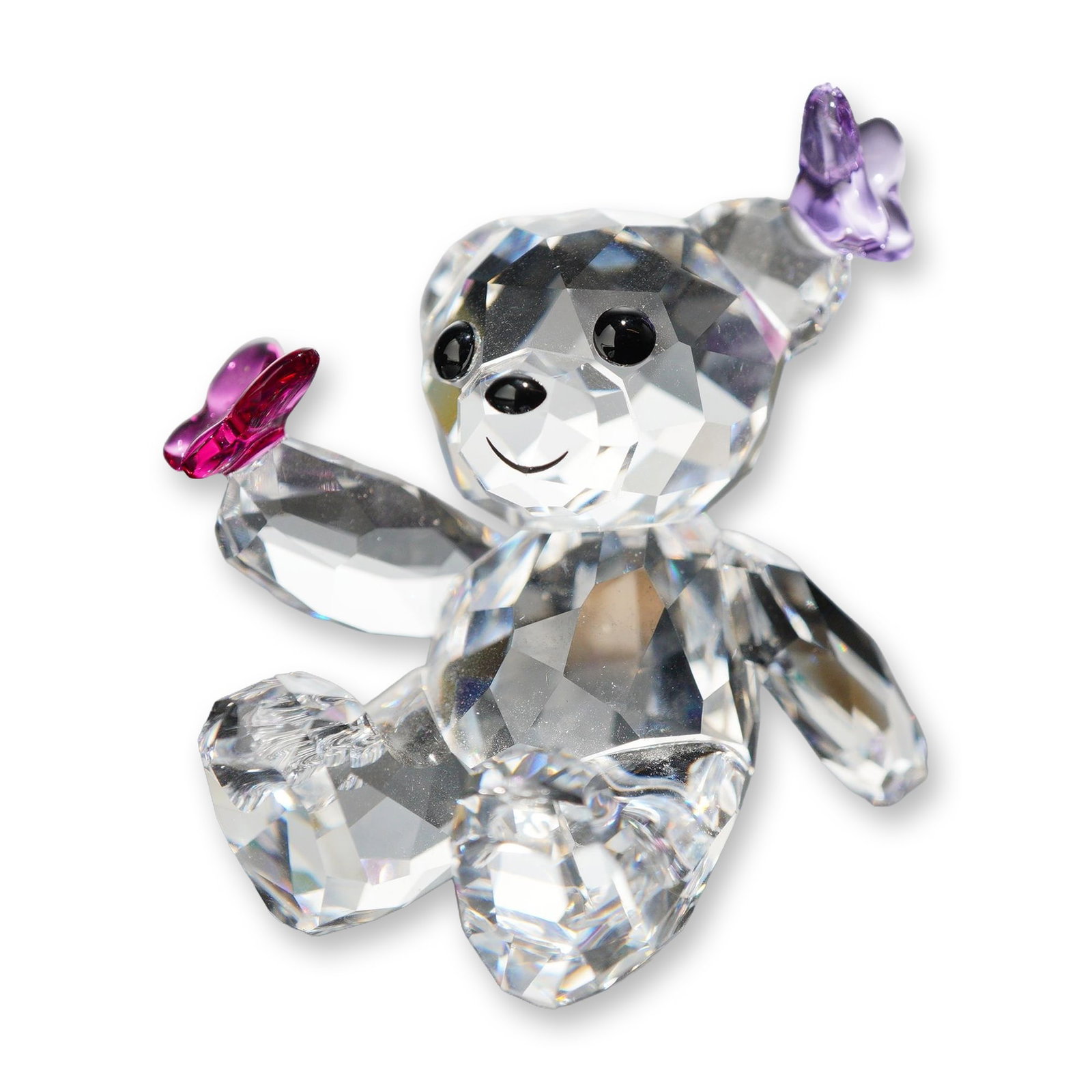 Swarovski Crystal Kris Bear Playful Butterflies Figurine: Swarovski lead crystal figurine from the Kris Bear collection, titled Playful Butterflies. The seated bear is constructed from faceted clear crystal with black crystal eyes and nose. The figurine feat
