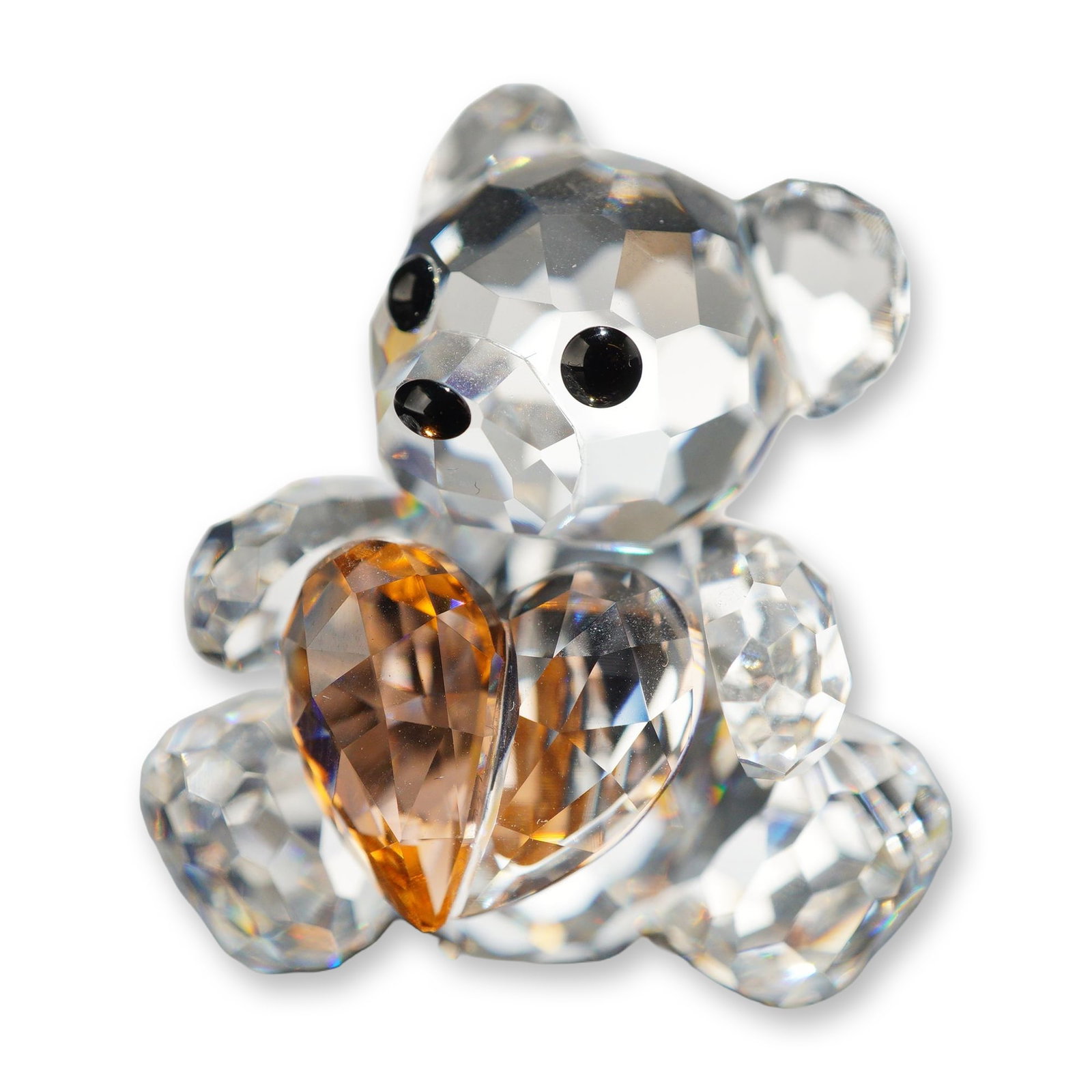 Swarovski Crystal Only For You Kris Bear Figurine: Swarovski faceted lead crystal figurine from the Kris Bear collection, titled Only for You. The seated bear is depicted holding a honey-amber colored faceted crystal heart. The piece features jet blac