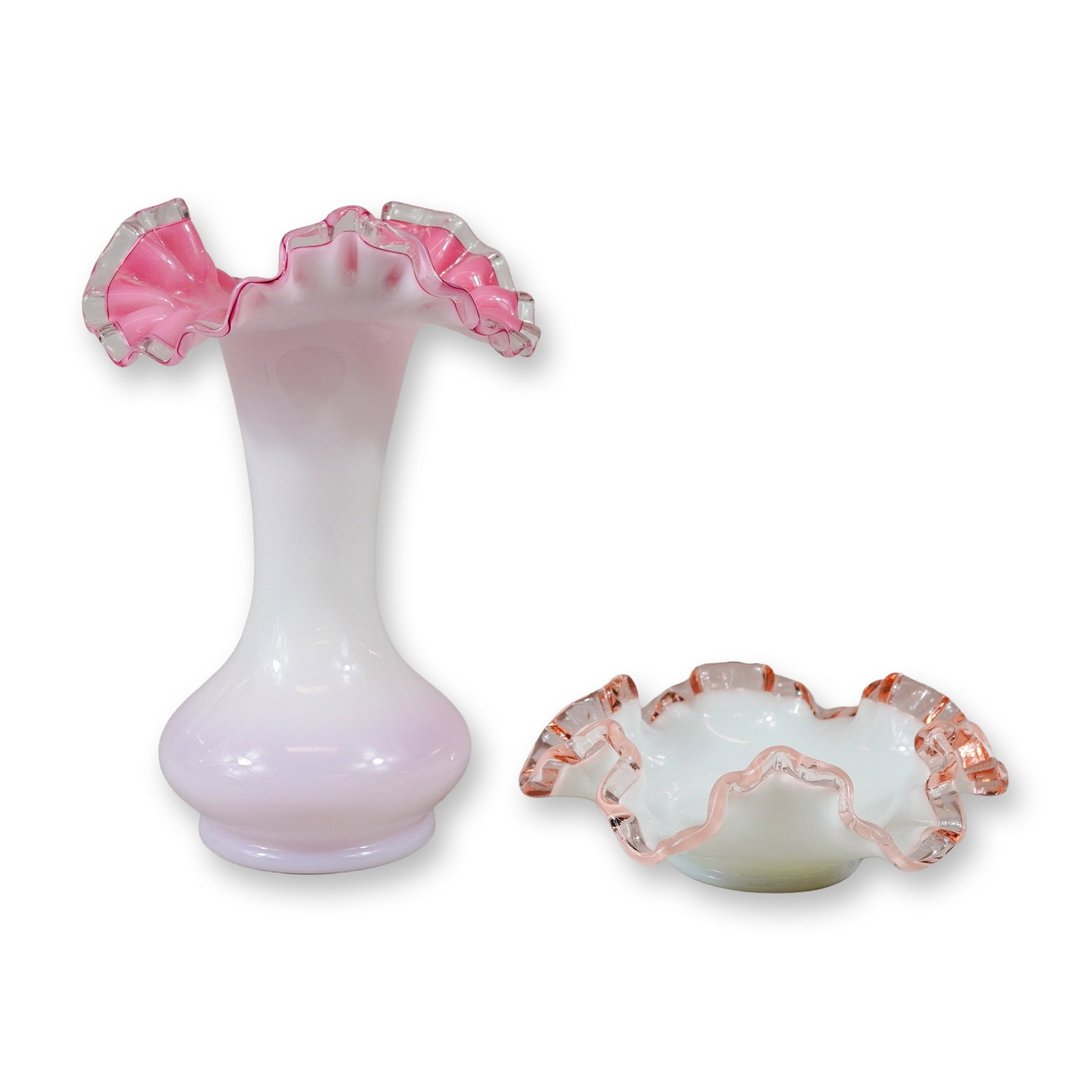 Two Fenton Style Peach Crest Pink and White Art Glass Pieces with Wavy Ribbon Edges: This lot features two pieces of cased art glass in the Peach Crest style, attributed to Fenton Art Glass. The group consists of a vase and a ruffled bowl. Both pieces are crafted using a casing techni