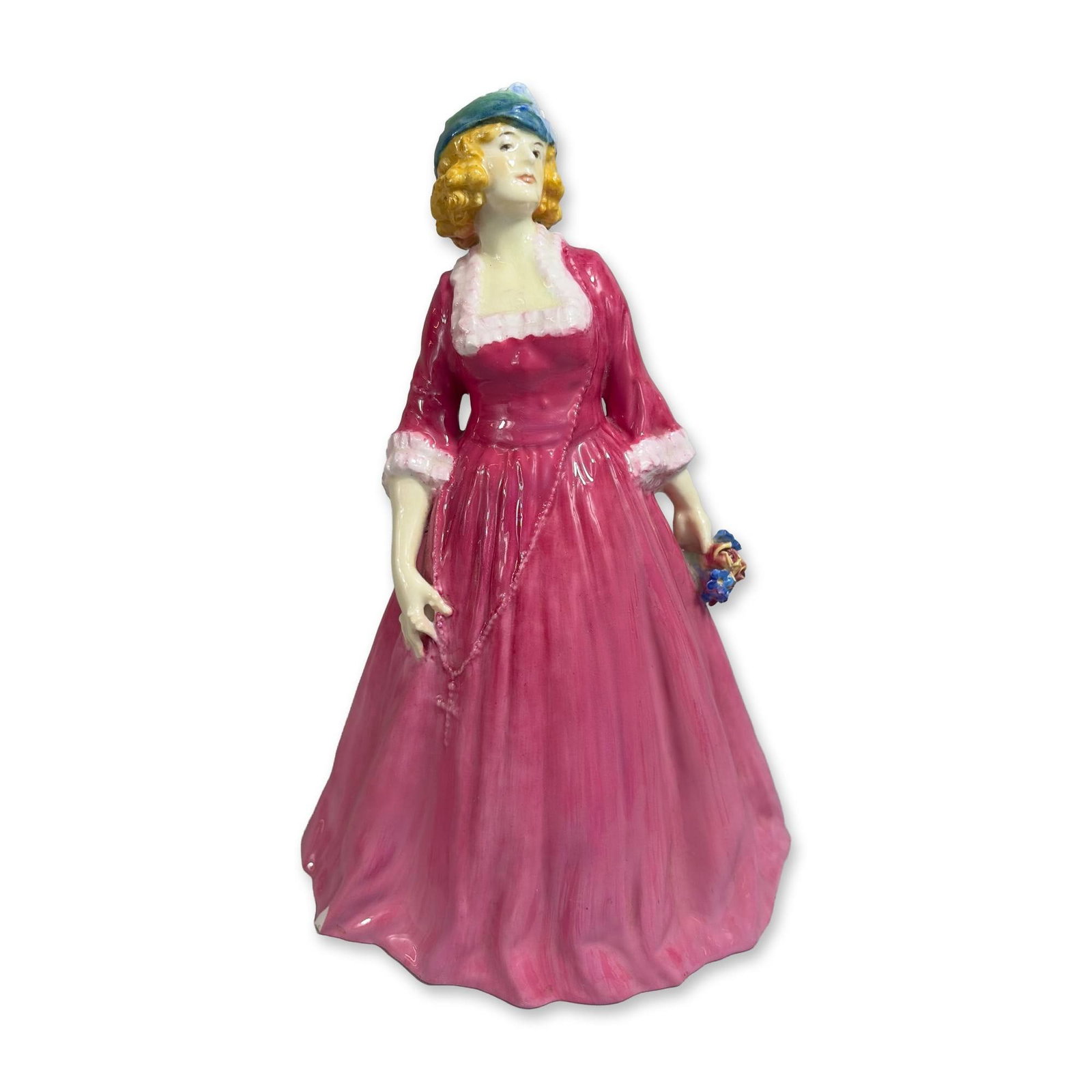 Royal Doulton Rosamund HN1497 Porcelain Figurine: The figure is depicted in a voluminous pink layered gown with white ruffled trim at the neckline and sleeves, wearing a bonnet in shades of blue, green, and yellow while holding a small bouquet of blu