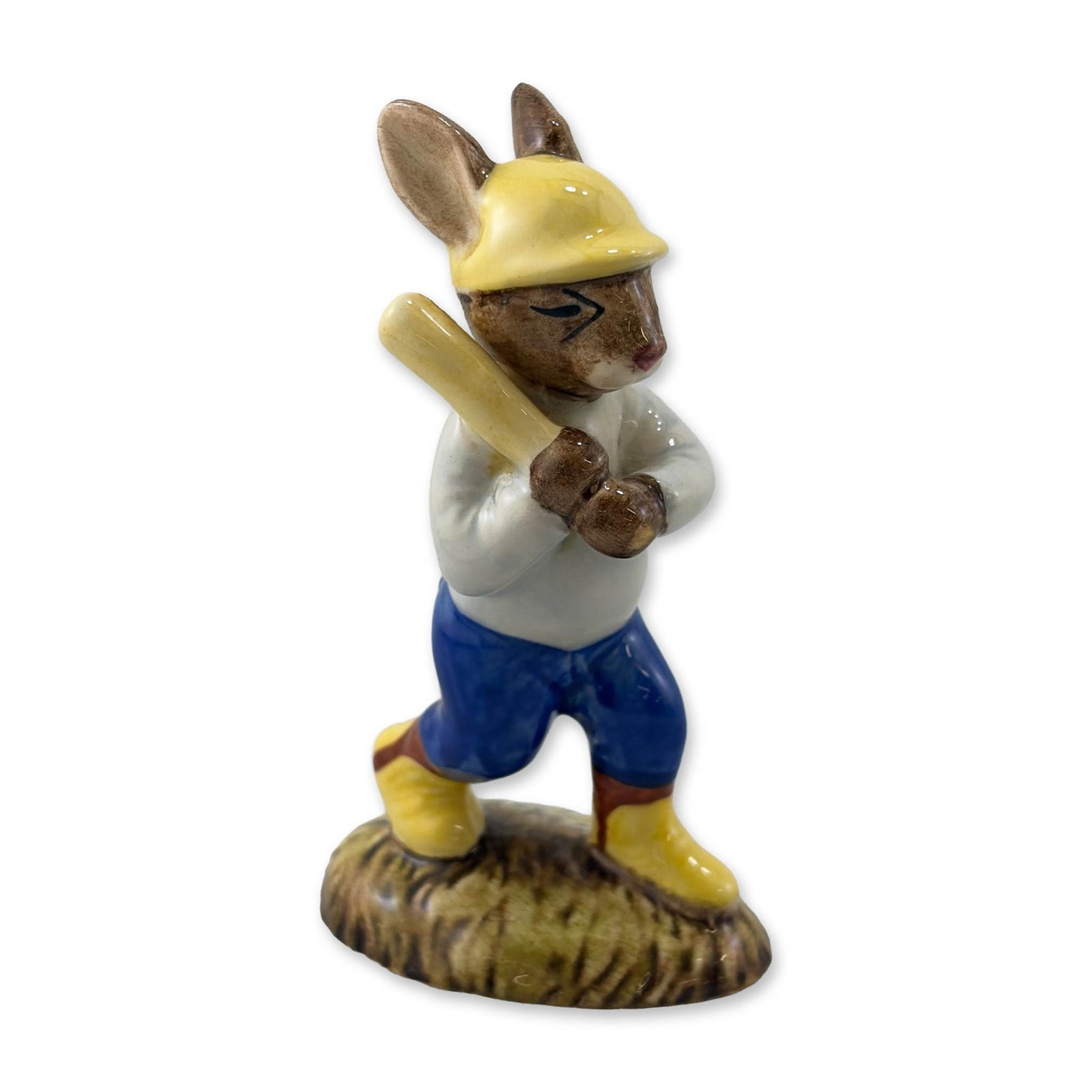 Royal Doulton Home Run Bunnykins Figurine DB43: Royal Doulton, England. Home Run Bunnykins figurine in glazed porcelain, model DB 43. The figure depicts a rabbit baseball player in mid-swing, wearing a yellow batting helmet and a white jersey with 