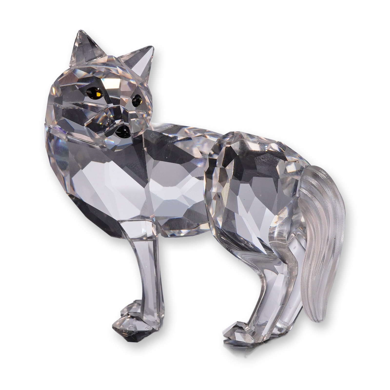 Swarovski Crystal Figurine, Wolf: Crafted in clear faceted lead crystal, the figure features a textured frosted crystal tail, amber-colored eyes, and a black nose. Marked with an acid-etched Swarovski swan logo and copyright symbol on