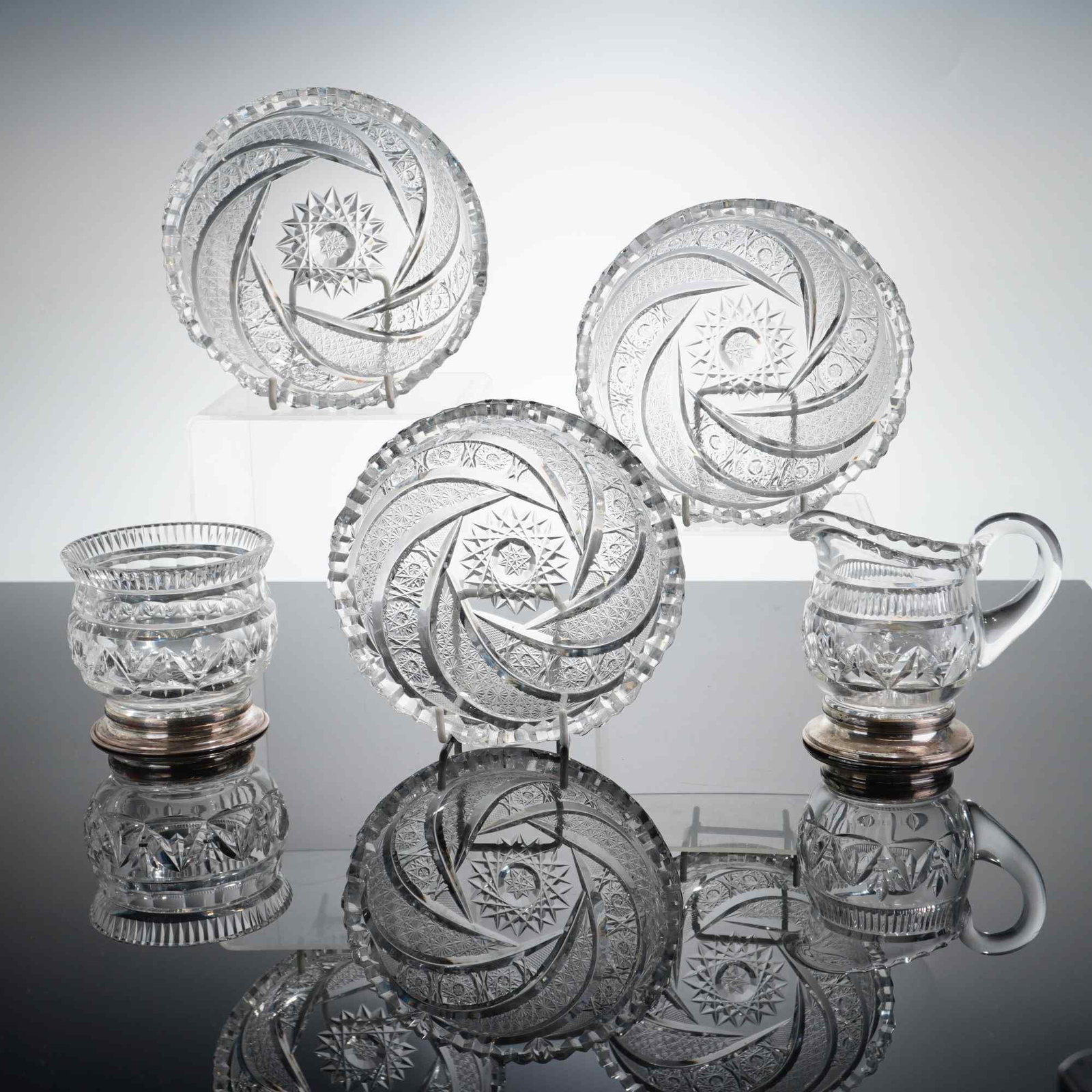 Group of Five American Brilliant Cut Glass Tableware Pieces: American Brilliant Period style cut glass grouping, late 19th to early 20th century. The collection comprises five pieces: three matching round dishes, one creamer with a sterling silver foot, and one