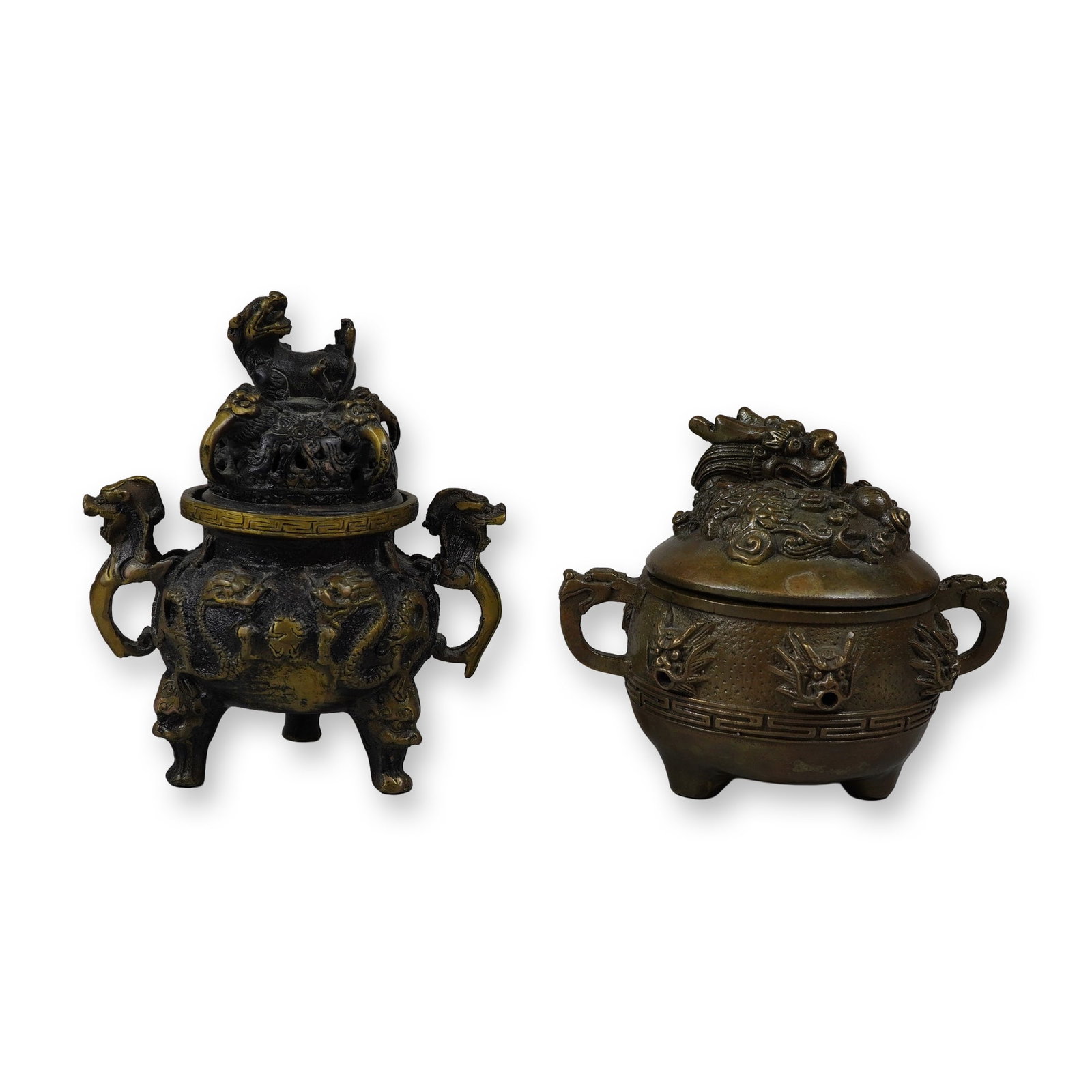 2pc Asian Themed Brass Dragon Incense Burners: This lot features two Asian-style brass incense burners with dragon motifs. The first burner has a tall tripod form with a pierced lid surmounted by a guardian lion (Shi-Shi) finial. Dragons in high r