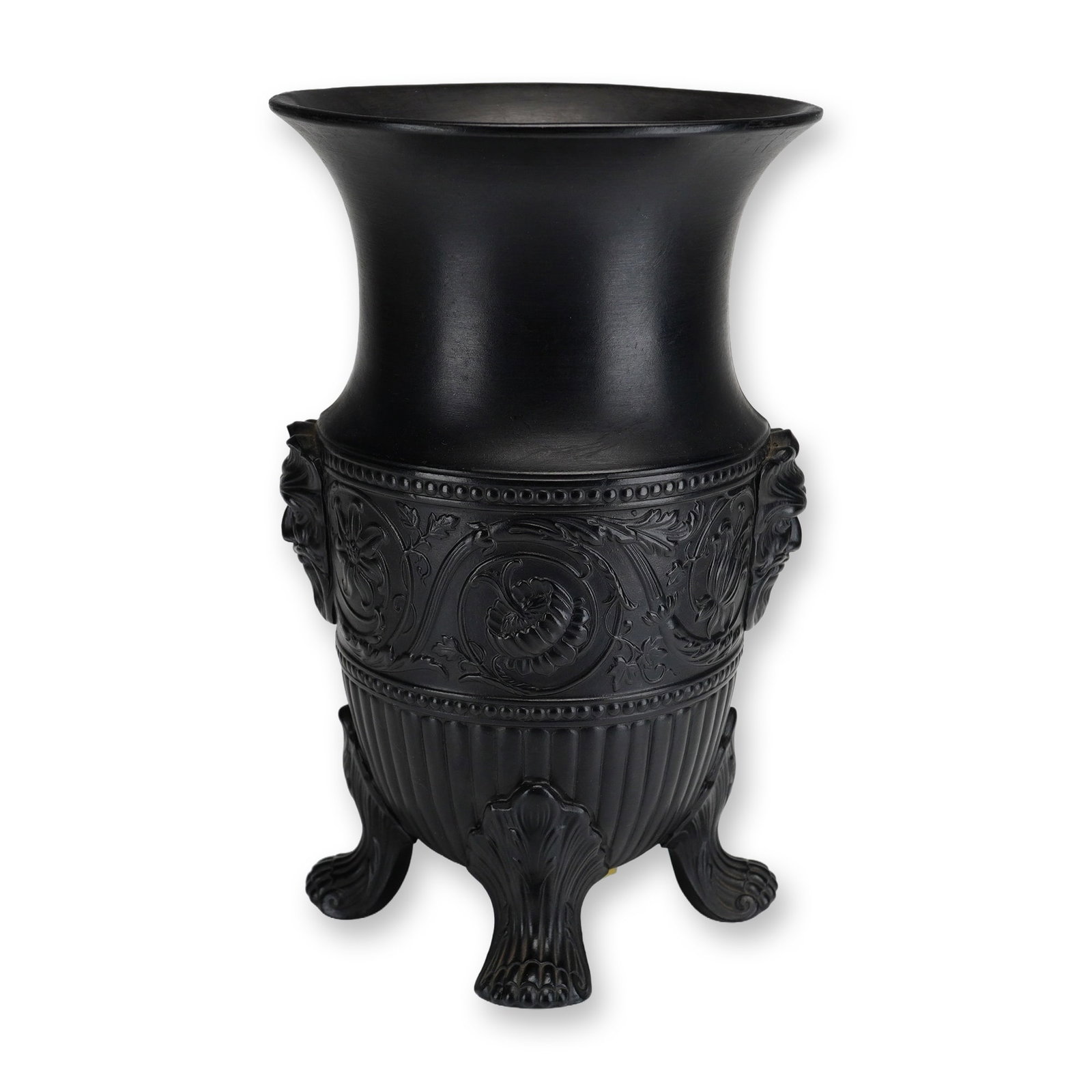 Wedgwood Black Basalt Footed Vase with Satyr Masks: A Wedgwood black basalt stoneware footed vase featuring a flared rim above a tapering neck and a bulbous body supported by four ornate, foliate-form feet. The central band of the body is decorated in 