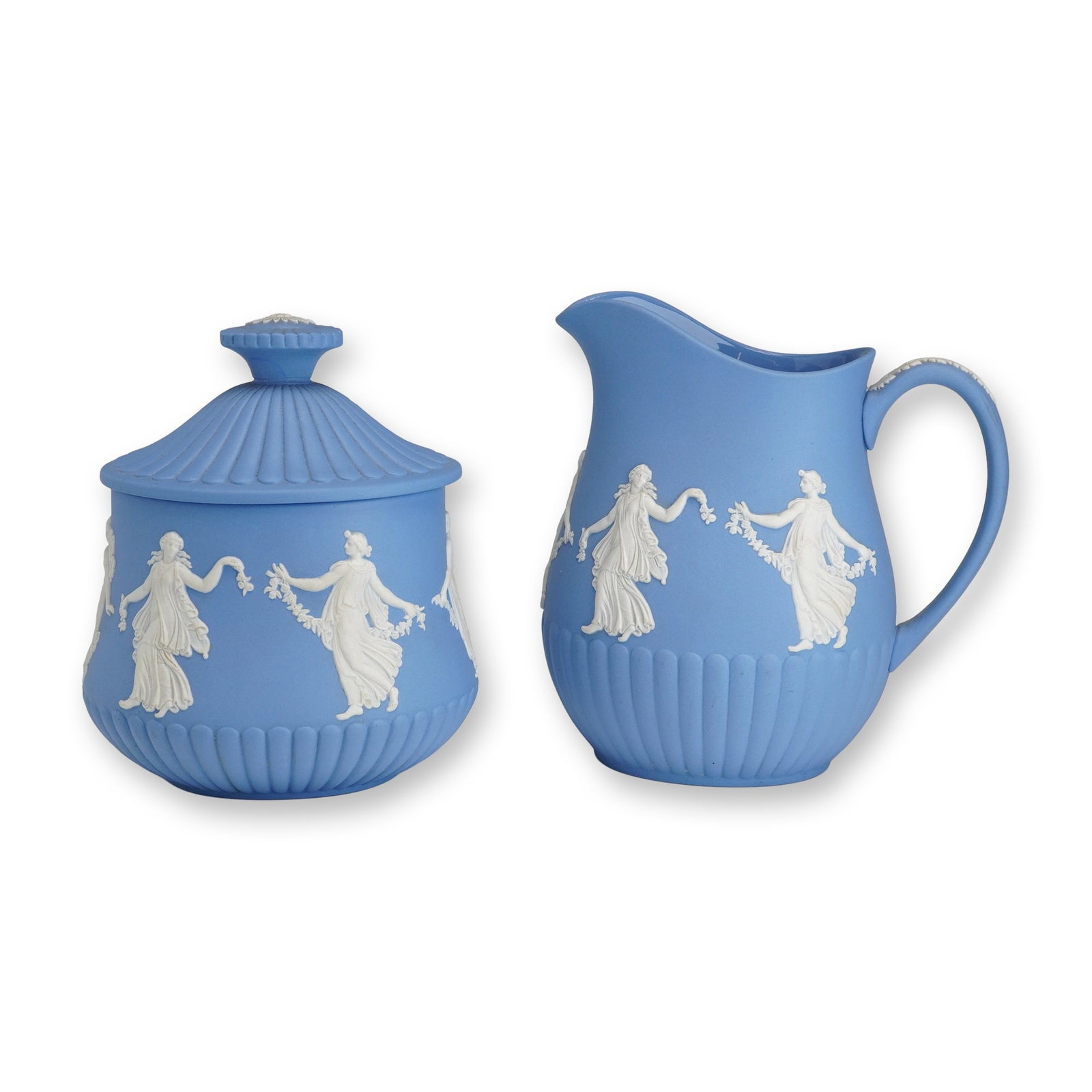 2pc Wedgwood Jasperware Lidded Sugar Bowl and Creamer: This lot consists of a two-piece Wedgwood Jasperware service set, including an oval lidded sugar bowl and a matching cream pitcher. Both pieces are constructed from light blue stoneware with a matte, 